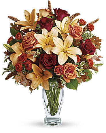 Teleflora's Fall Fantasia - Roses, lilies and oak leaves create a fantasy of fall flowers. Send this tall, elegant arrangement to wish someone a happy autumn or joyous Thanksgiving. The warm color palette and Couture Vase make a stylish seasonal statement. Orange, dark orange and red roses blend with orange asiatic lilies, green salal and pitta negra. Subtle seasonal elements include dried oak leaves and millet. Presented in Teleflora's chic Couture Vase. Orientation: One-Sided