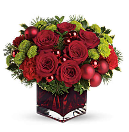 Teleflora's Merry &amp; Bright - This Christmas bouquet stays true to its name! Merry details including red Christmas ornament balls, Douglas fir and variegated holly are mixed with bright green button chrysanthemums in a jolly red cube vase. Lush roses and carnations add to the seasonal splendor. A gorgeous red cube vase is filled with red roses, red carnations, green button chrysanthemums, variegated holly, Douglas fir and English boxwood. Shiny and matte Christmas balls add a festive touch. Orientation: All-Around