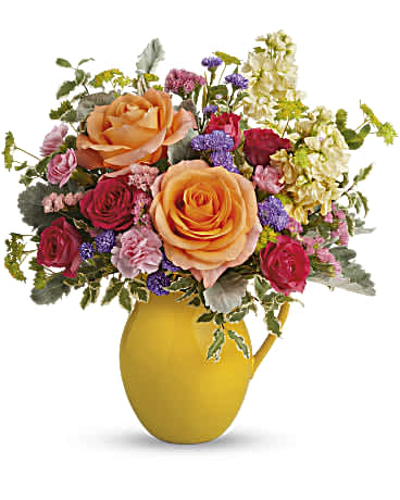 Teleflora's Be Bright Bouquet - Pour on the sunshine! Filled with radiant roses, this cheerful yellow pitcher sprinkles happiness on any occasion and makes a great food-safe addition to any home. Peach roses, hot pink spray roses, miniature pink carnations, light yellow stock, large purple monte cassino asters and pink sinuata statice are accented with bupleurum, pitta negra and dusty miller. Teleflora's Be Bright Bouquet is delivered in Teleflora's Sunny Day Pitcher. Orientation: All-Around
