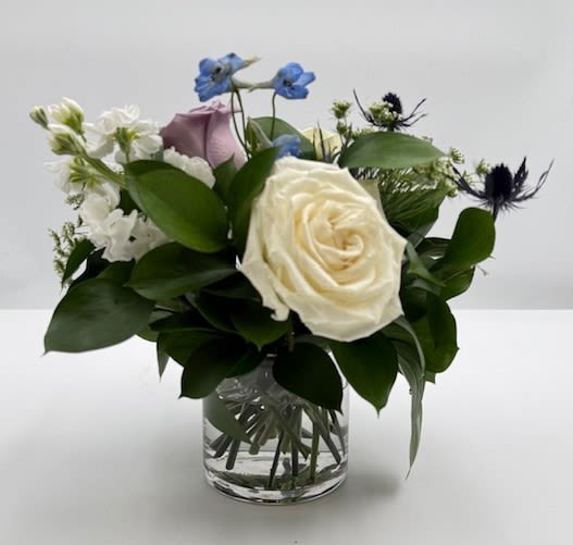   Lil Pick Me Up - We all have days when we could use a little pick me up. White and lavender roses, stock and delphinium make up this sweet gesture arrangement.  A scaled down arrangement with the same care and quality of our larger designs.