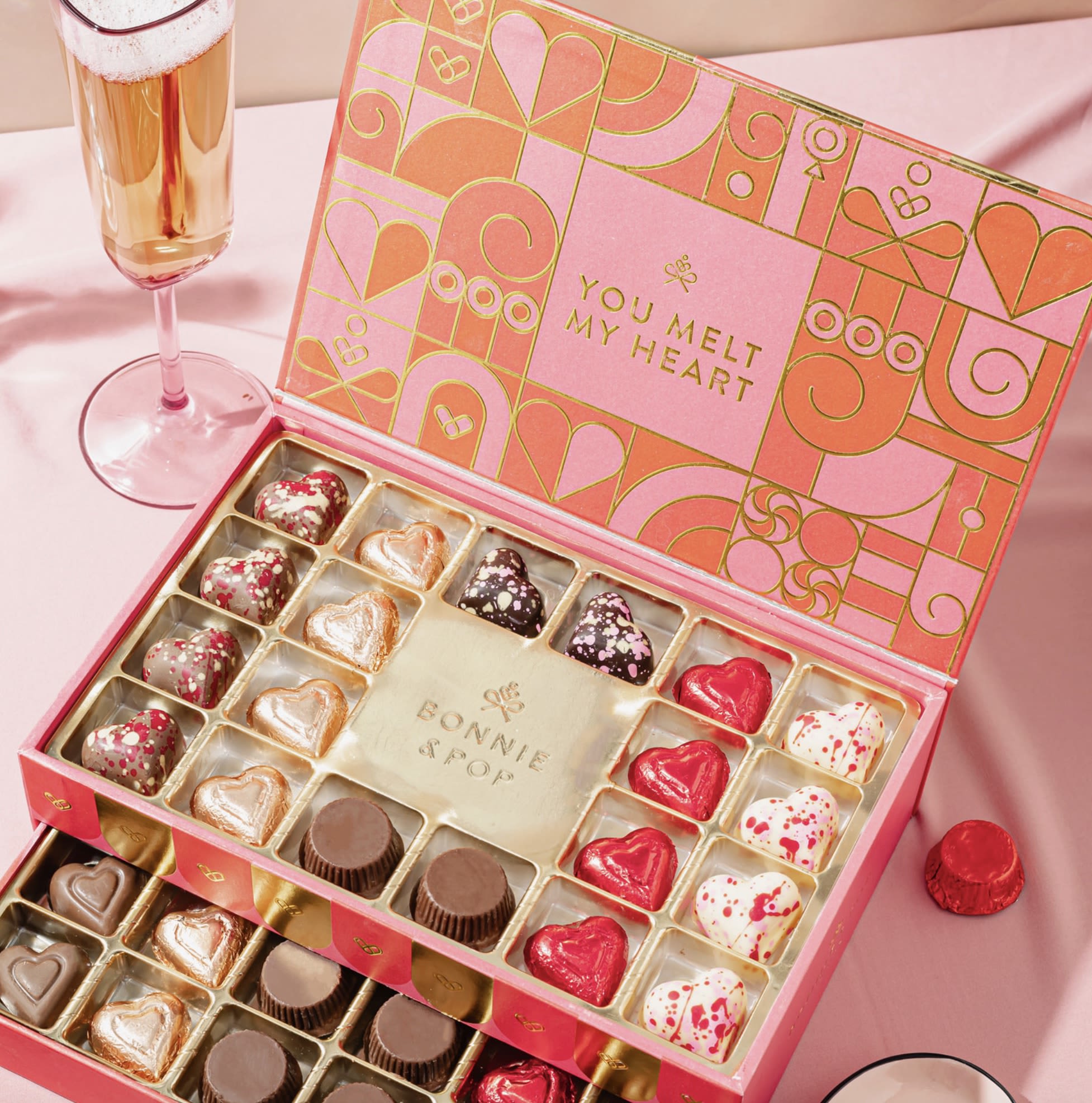 Two-Tier Treasures Of The Heart - Cupid called, and he’s jealous of this masterpiece! Unlock the magic of romance with this luxurious drawer box filled with handcrafted chocolates. Each drawer reveals an irresistible selection of creamy truffles,  and heart-shaped delights, all dressed in rich reds, golds, and luscious chocolate tones. Bonnie &amp; Pop NY