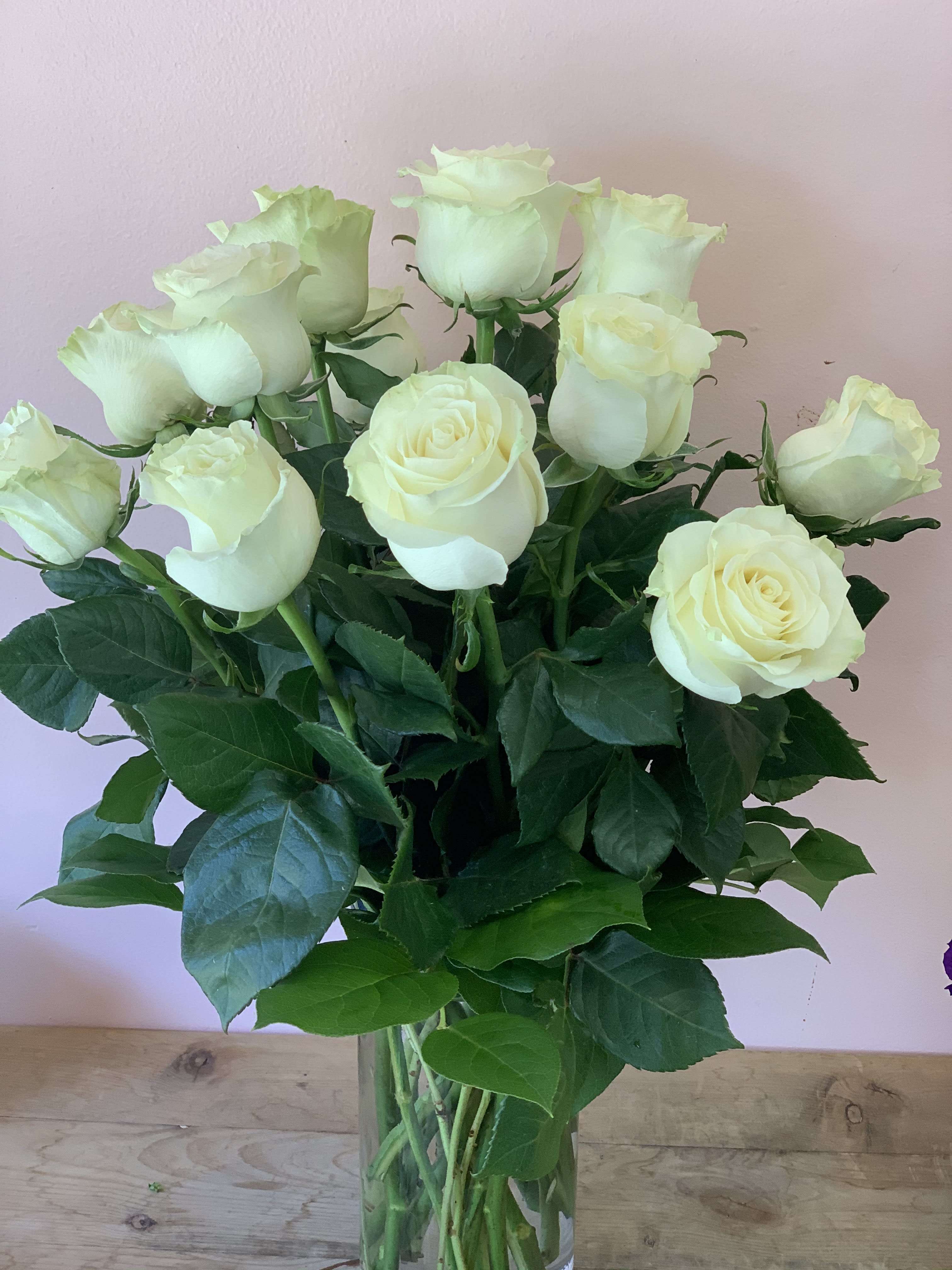 12 long stem white roses - W813 - Romance blossoms beautifully within this elegant bouquet. The serenity and innocence of cream-colored roses is in delightful juxtaposition with fresh greens. It's as romantic as a stroll through the English countryside. A dozen white roses are perfectly arranged in a  glass vase.Approximately 17" W x 15" H Orientation: All-Around As Shown : W813