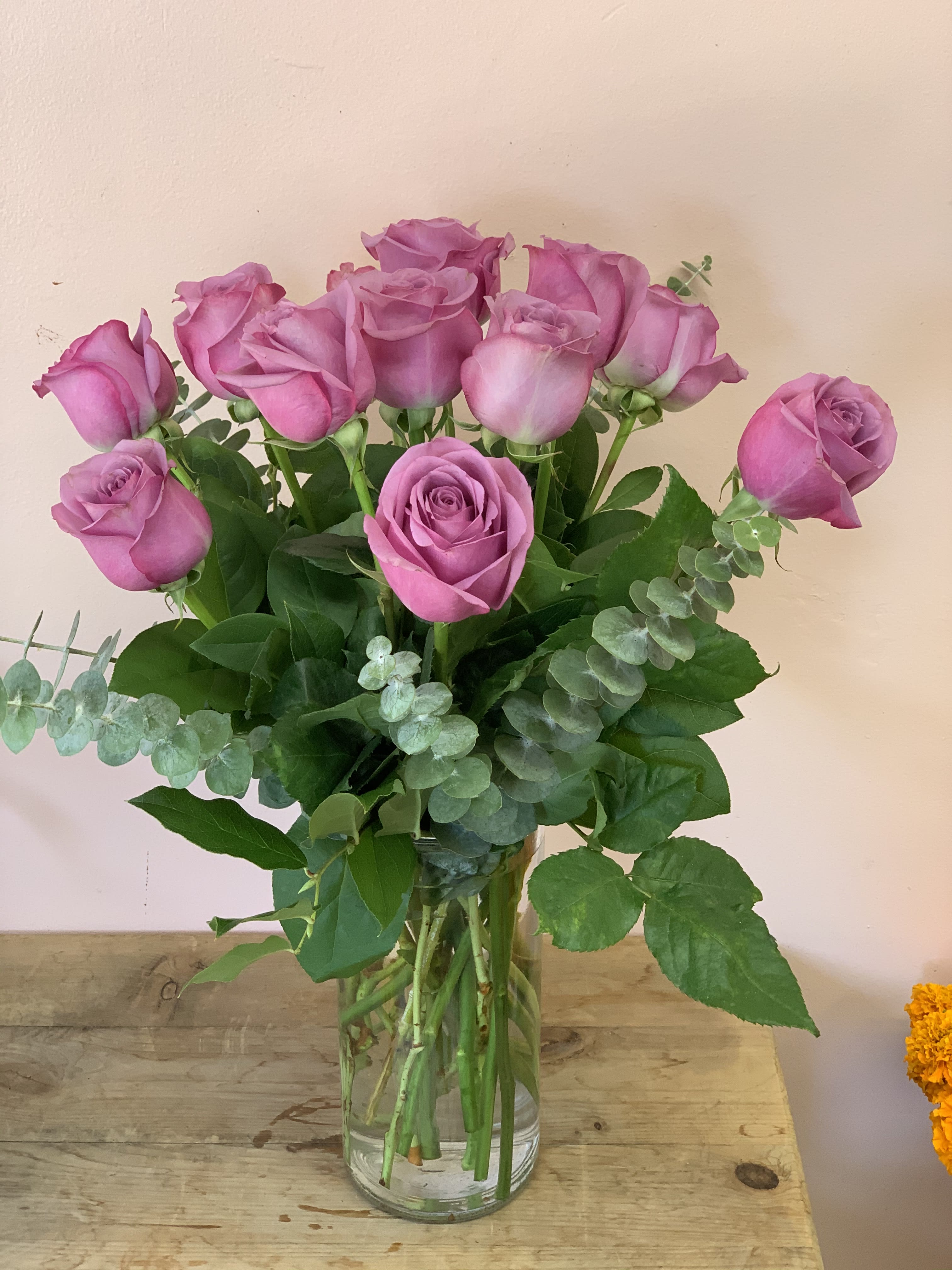 A Dozen Lavender Roses - W816 - Adoration and enchantment with a dash of regal majesty - the lavender rose says it all. With tone-on-tone accents this luxurious dozen offers a striking yet softly feminine floral bouquet for any occasion. 12 lavender roses with variegated pittosporum and salal arrive in a classic glass urn vase. Approximately 14" W x 16" H Orientation: All-Around As Shown : W816