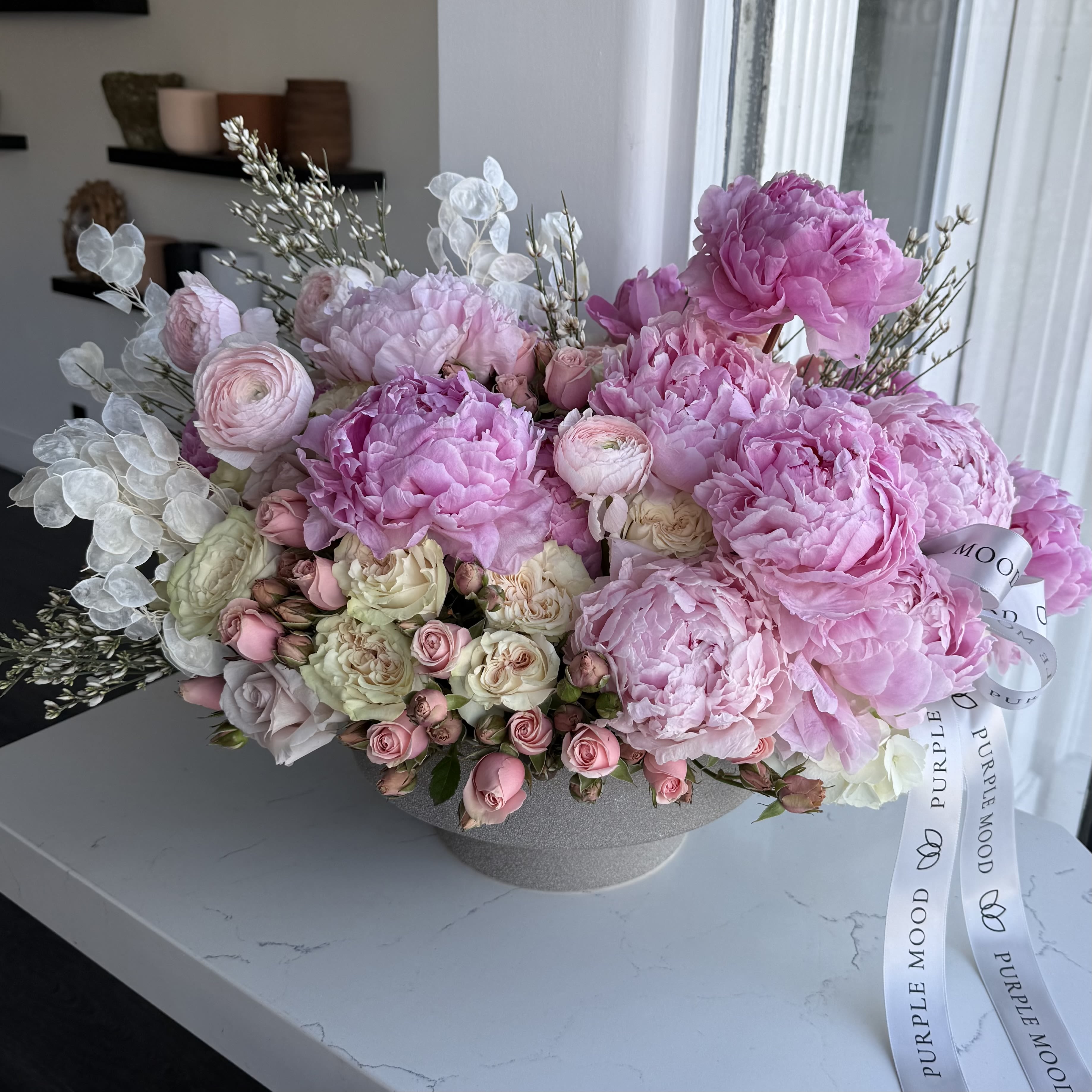 Peony Couture Vase - A bold and romantic arrangement featuring premium red roses, striking red anthuriums, and soft blush hydrangea, accented with delicate seasonal blooms. Wrapped in elegant Valentine-red and soft pink layers, this bouquet is designed to make hearts melt. Perfect for expressing love, passion, and deep affection on Valentine’s Day or any romantic occasion.