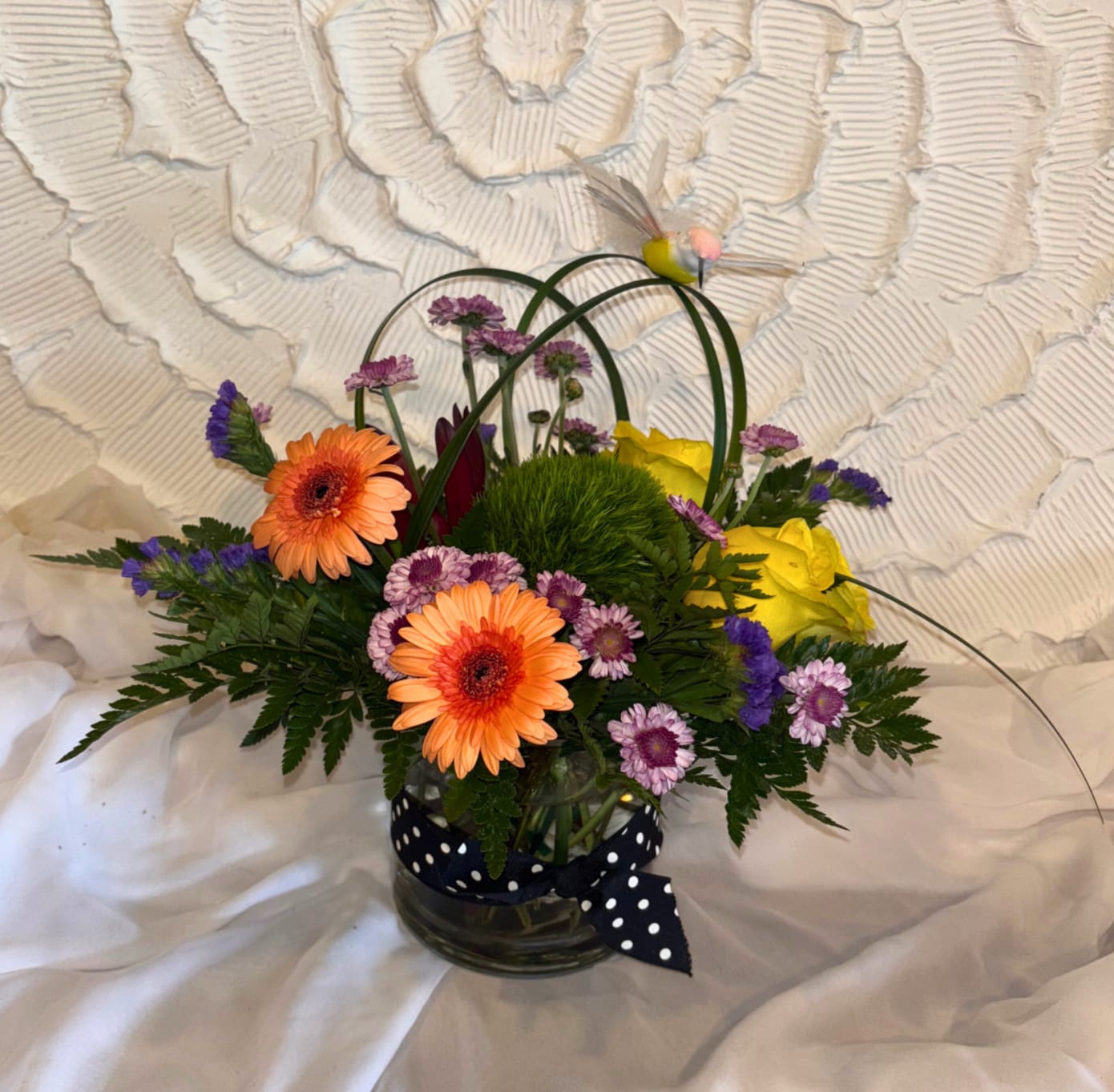 Sweet Song Bird - Here is another Popular One! Great for many occasions! This Compact Vase Arrangement is made with Mini Gerbera Daisies, Roses,  Poms, Safari Sunset,  Green Trick Dianthus, Lily Grass loops, etc. A Crowd Pleaser!