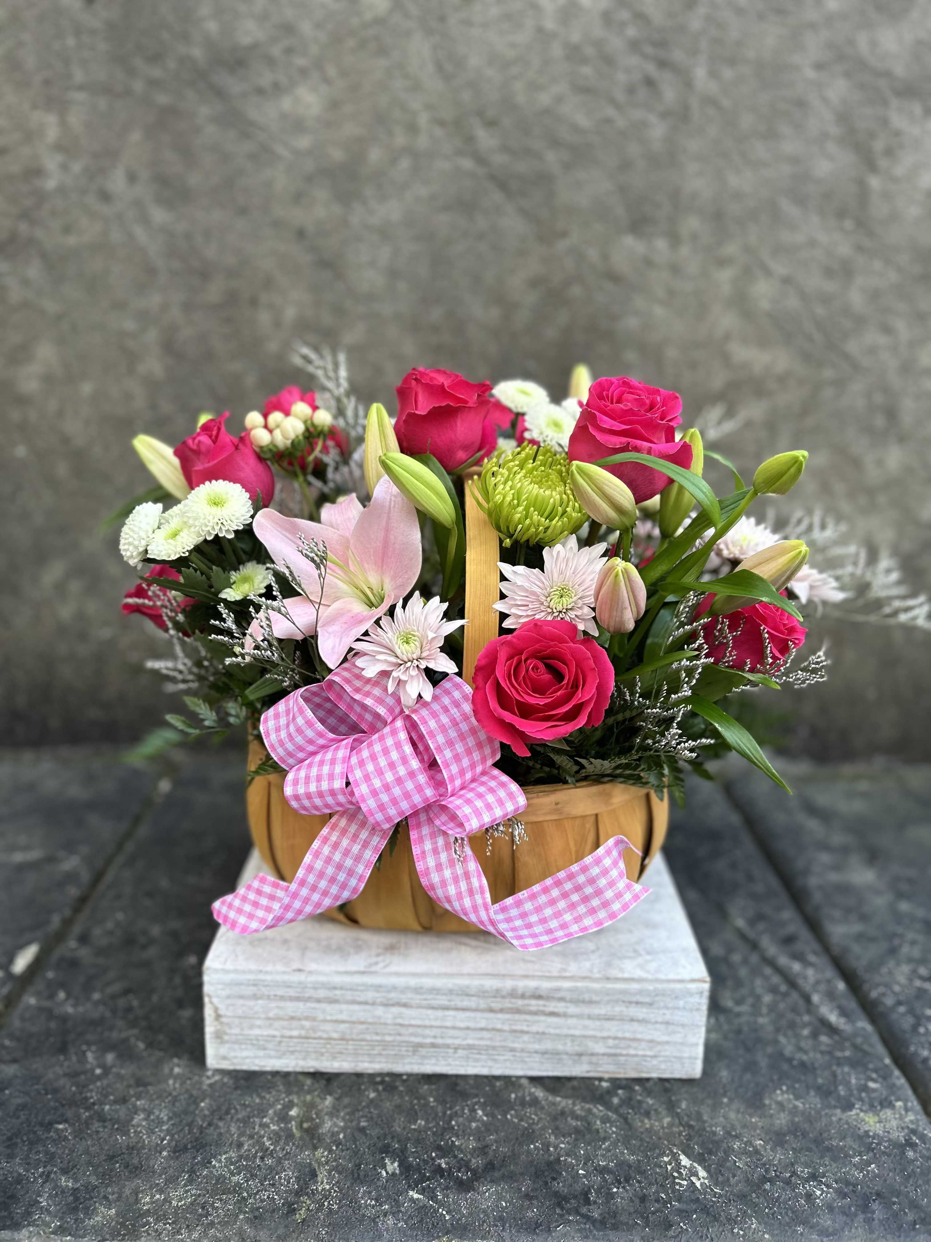 Pretty in pink - Hot pink roses, chrysanthemums, button poms, pink lilies, hypericum, greenery, and blooming fillers in a large basket.   *Reasonable substitutions may be made due to floral availability. Will have the same look and feel. 