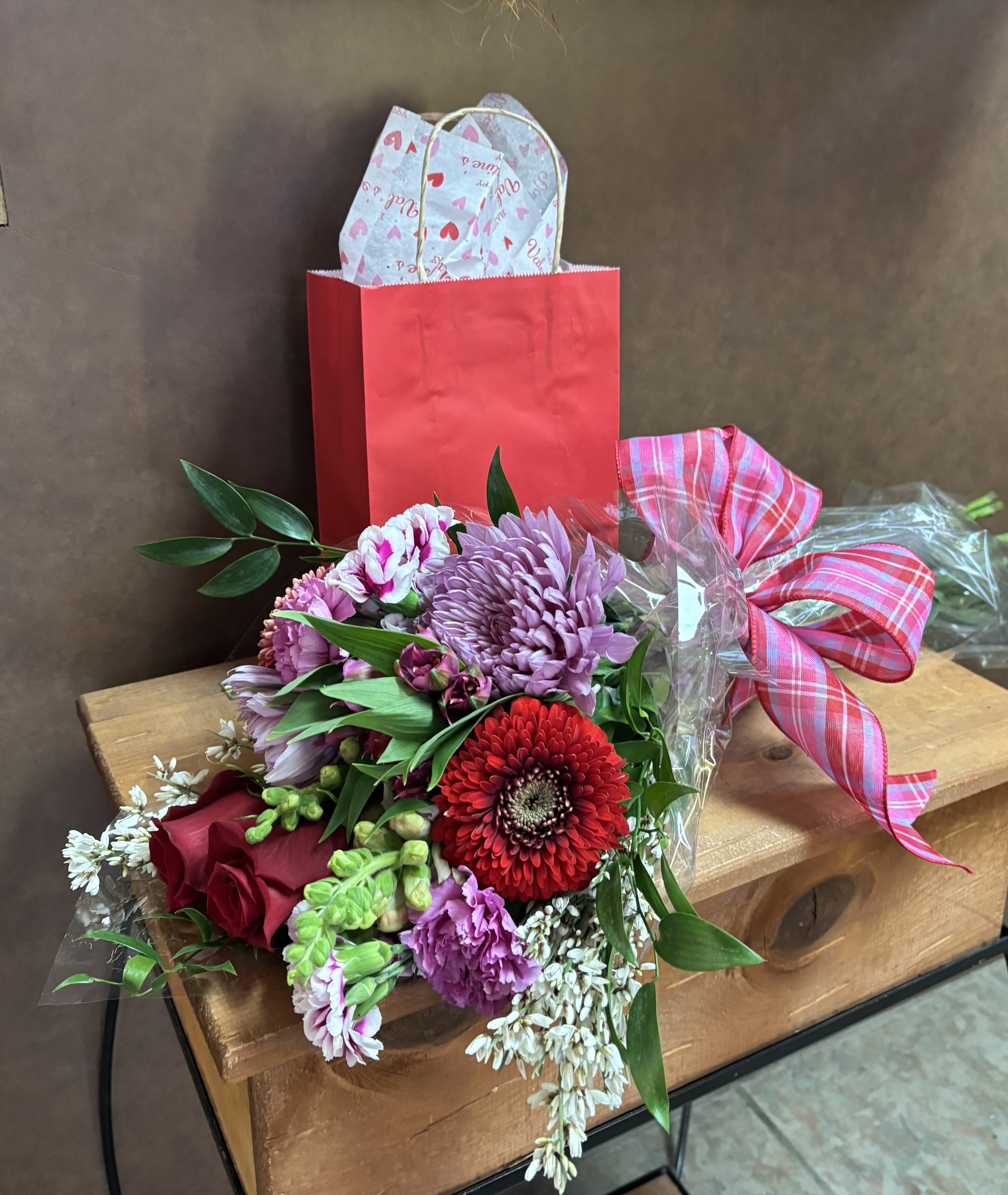 Wrapped with Love &amp; Sweetness - A modern interpretation of the classic "boxed mixed bouquet" updated to cellophane wrapping to illuminate the beauty and accentuate the presentation of this gorgeous collection of mixed florals. In addition to the lovely blooms, a Valentine gift bag of strip style boxed cherry cordial chocolates will be included. Flower choices by the designer are seasonal and occasion appropriate. Roses will be included in each bouquet along with other coordinating flower selections, fillers &amp; greens. Flowers and candy can't be beat!!