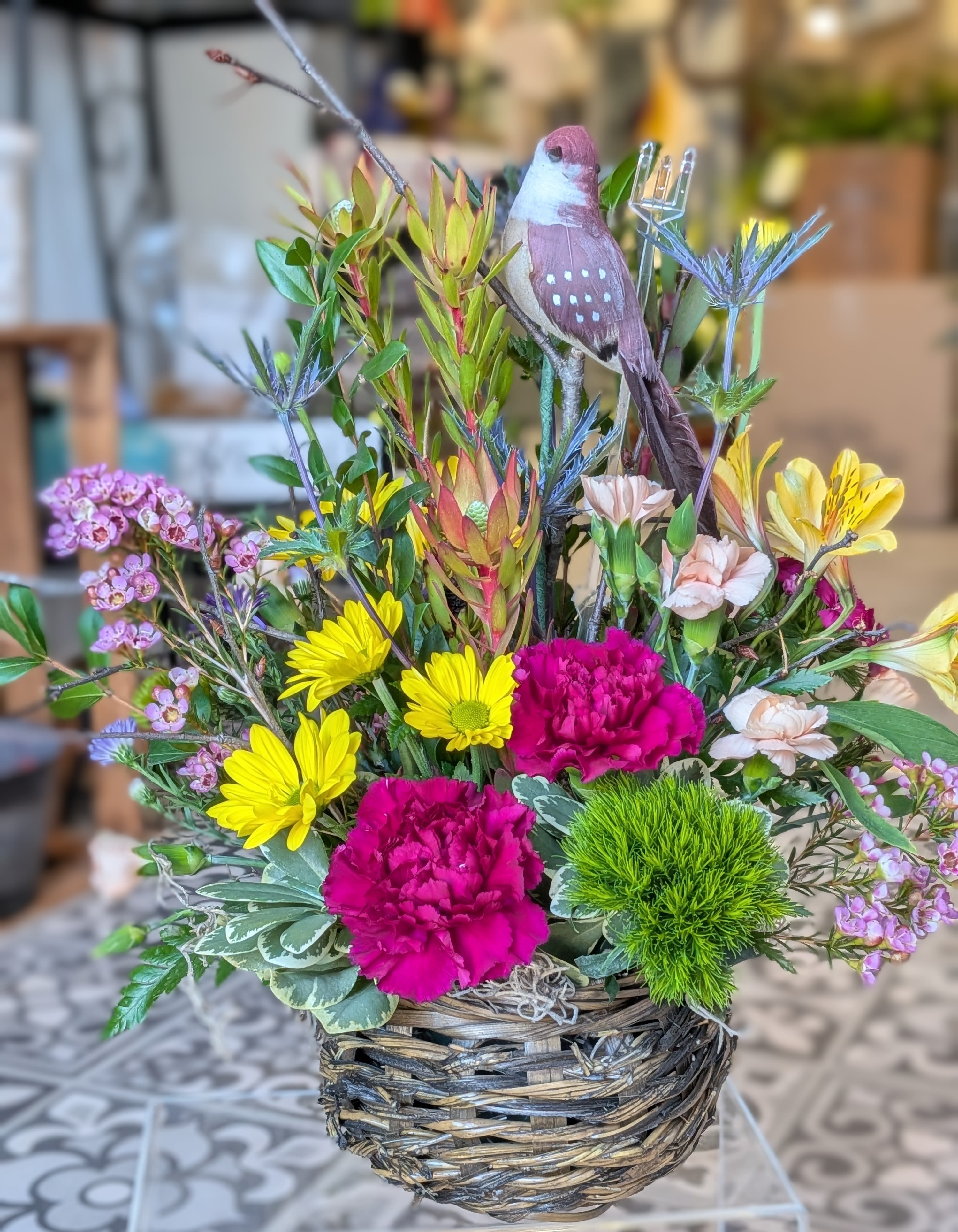 Nature's Feathered Friend - Honor and treasure the time spent together with this nature inspired bouquet  This is a designer choice arrangement. Flowers and colors may vary  All around 18Hx15W