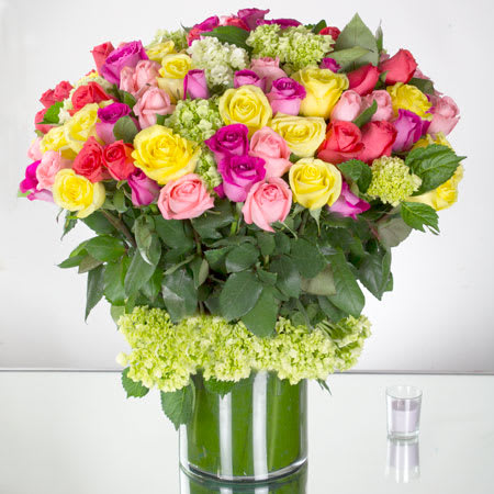 Lush Abundance (DB) - Prepare to be captivated by the sheer beauty and abundance of this extraordinary flower arrangement. Featuring 100 assorted roses in a splendid array of colors, complemented by delicate mini green hydrangea, all elegantly showcased in a large, transparent cylinder vase.