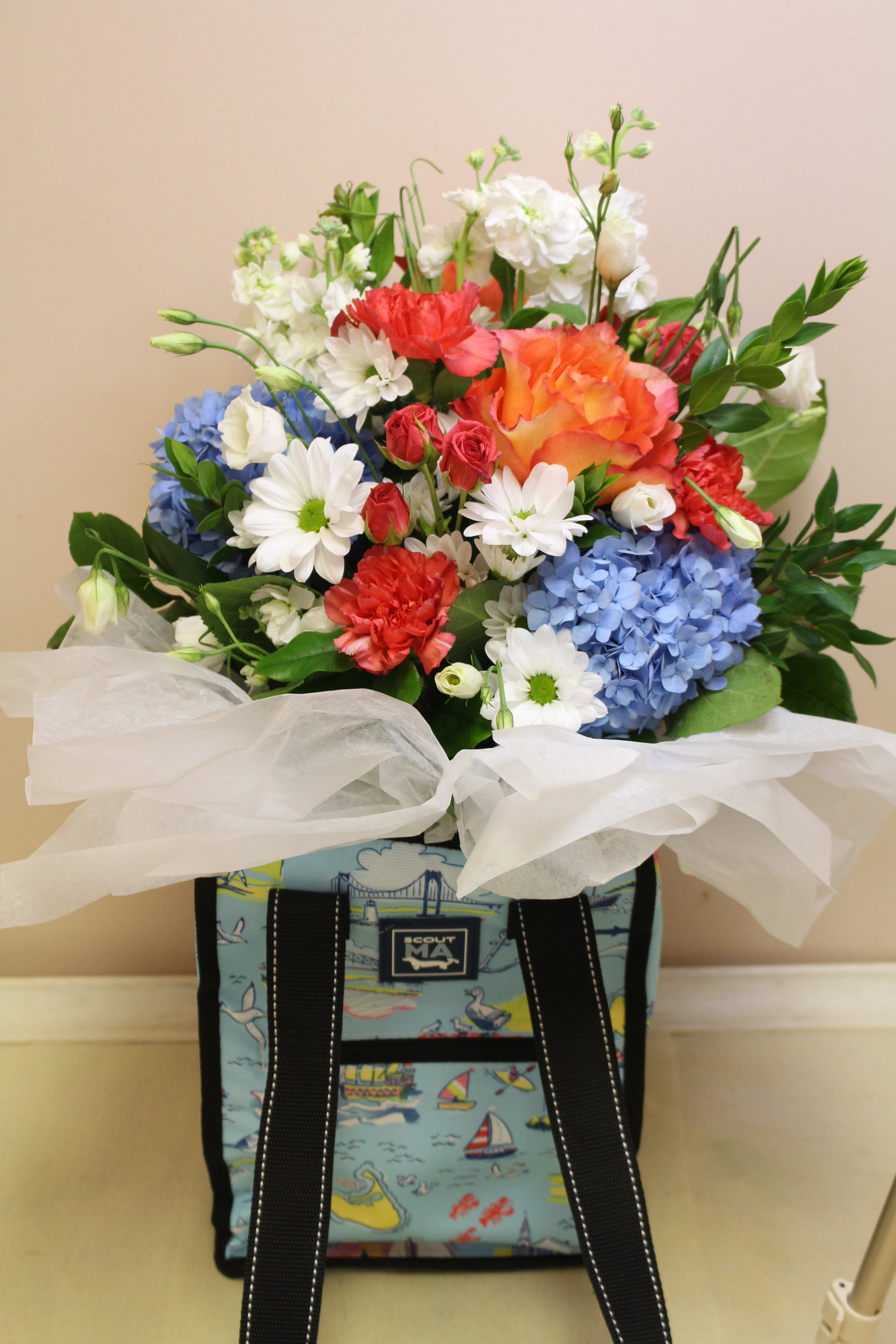 scout -  Massachusetts STATEment  collection Pleasure chest - A beautiful fresh arrangement filling a scout bag! Celebrate MASSACHUSETTS with this exclusive pattern!  From big, bustling cities to quaint seaside villages, Massachusetts is a state of wonder! This exclusive SCOUT pattern—part of our year-round STATEment Collection—is designed to celebrate this fabulous state wherever life takes you. Great for gifting! (More states available.)   Ideal for family outings, this cooler fits a six pack or four wine bottles. It's just the right size to stack multiple food containers. There are two outside pockets to hold napkins and utensils, or candy bars (no judgement here!). Height 12.5" Depth 9" Width 9"  Wrapped, reinforced handles for easy carrying Zipper closure to keep drinks cooler for longer Heat-sealed, PVC-free liner Exterior zipper pocket can hold a bottle opener, utensils, or last minute items Slip pocket on back