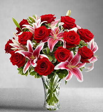 Roses and Lily Bouquet - Shown as Standard A dozen red roses with pink lilies come arranged in a clear glass vase. *We custom design this arrangement and use the freshest flowers available the day of delivery. The arrangement in this picture is an example of the size and style and may not feature the exact product shown.*