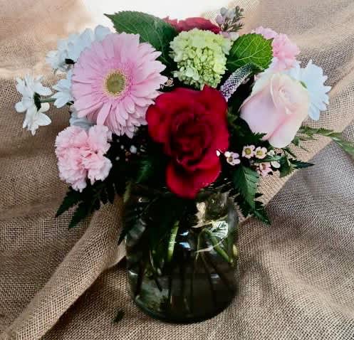 Deal for Valentine's Day - Nice assortment of red roses, white daisies and pink carnations in a cinched clear vase.