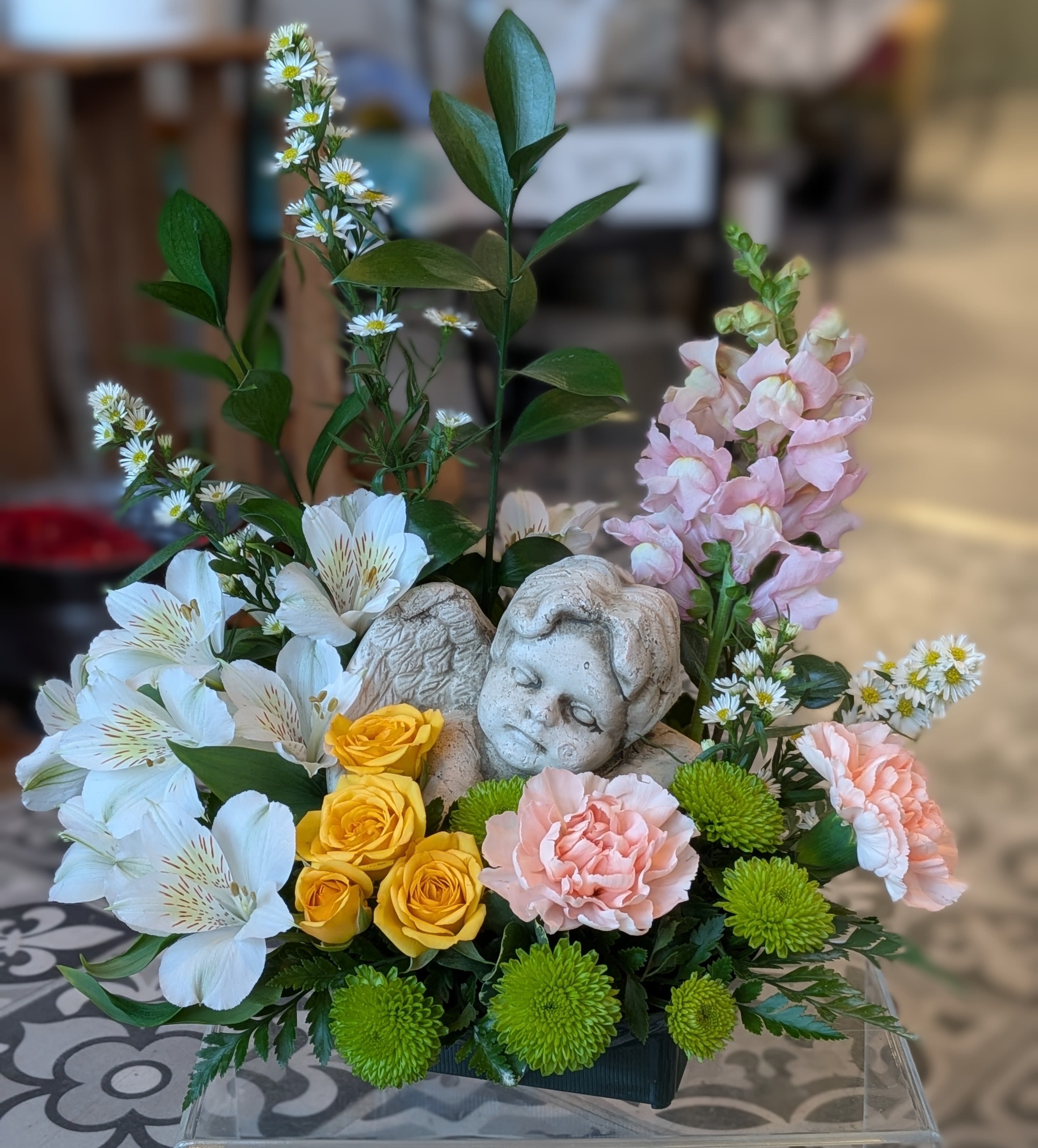 Angelic Stone Statue - Radiating grace and serenity, this bouquet surround keepsake with colorful florals. This arrangement is a designer choice so colors and flowers will vary. 14Hx14W One Sided
