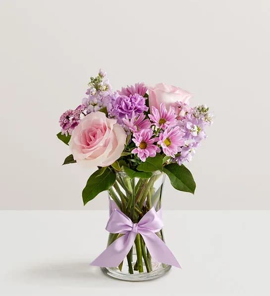 Daydream Bouquet 26 -  Just like a daydream. Our delightful lavender bouquet is gathered with accents of pink and lush greenery in a glass vase tied with a lavender satin ribbon that complements the delicate beauty of the blooms.