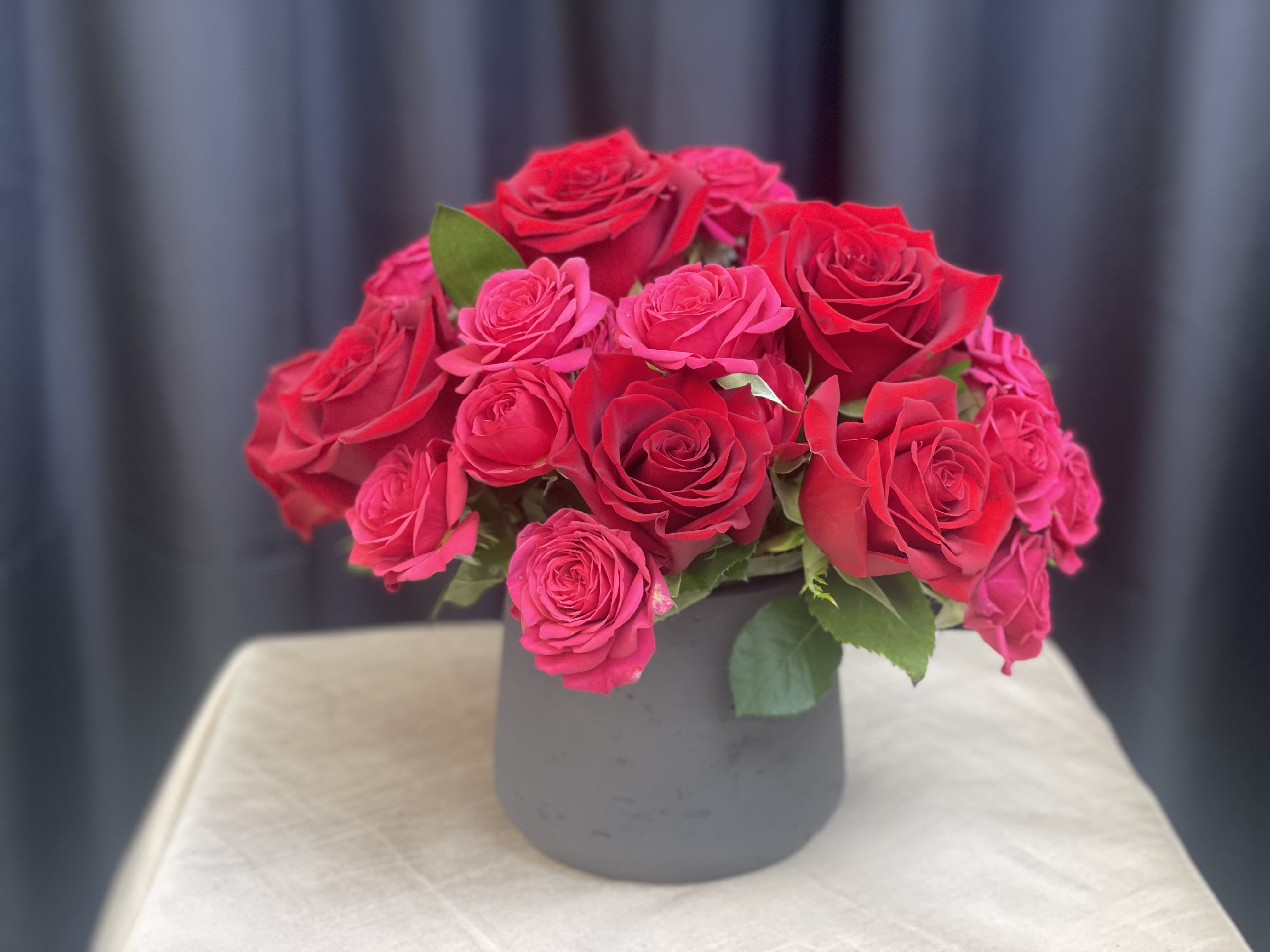 Velvet Current - Velvet Current is a bold expression of modern romance. Lush all-red roses create a rich, velvety base, while hot pink sweetheart roses weave through the arrangement like an electric pulse. The contrast is striking yet refined—classic passion softened by playful intensity.
