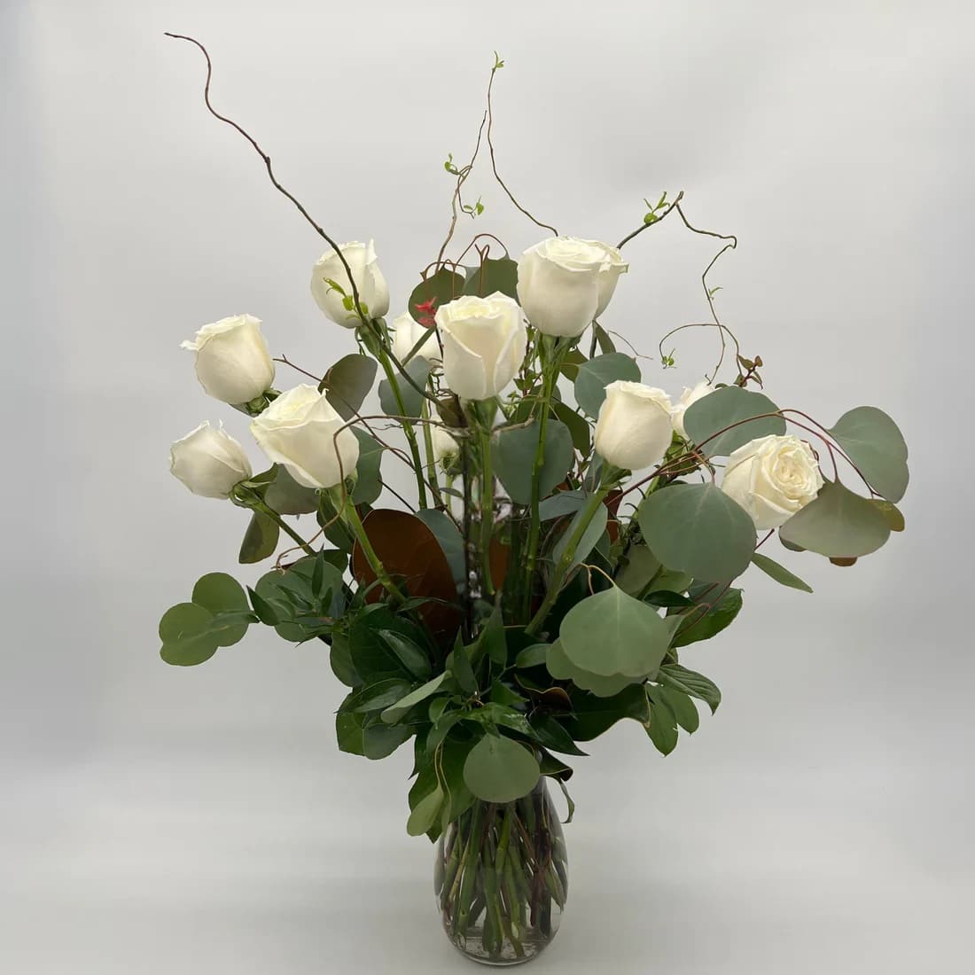 White Roses - Your choice of one dozen, one and a half, or two dozen beautiful white roses with foliage in a tall vase. Standard one dozen roses is pictured. Designer may need to make foliage substitutions based on our current inventory. Bloom Details Rose