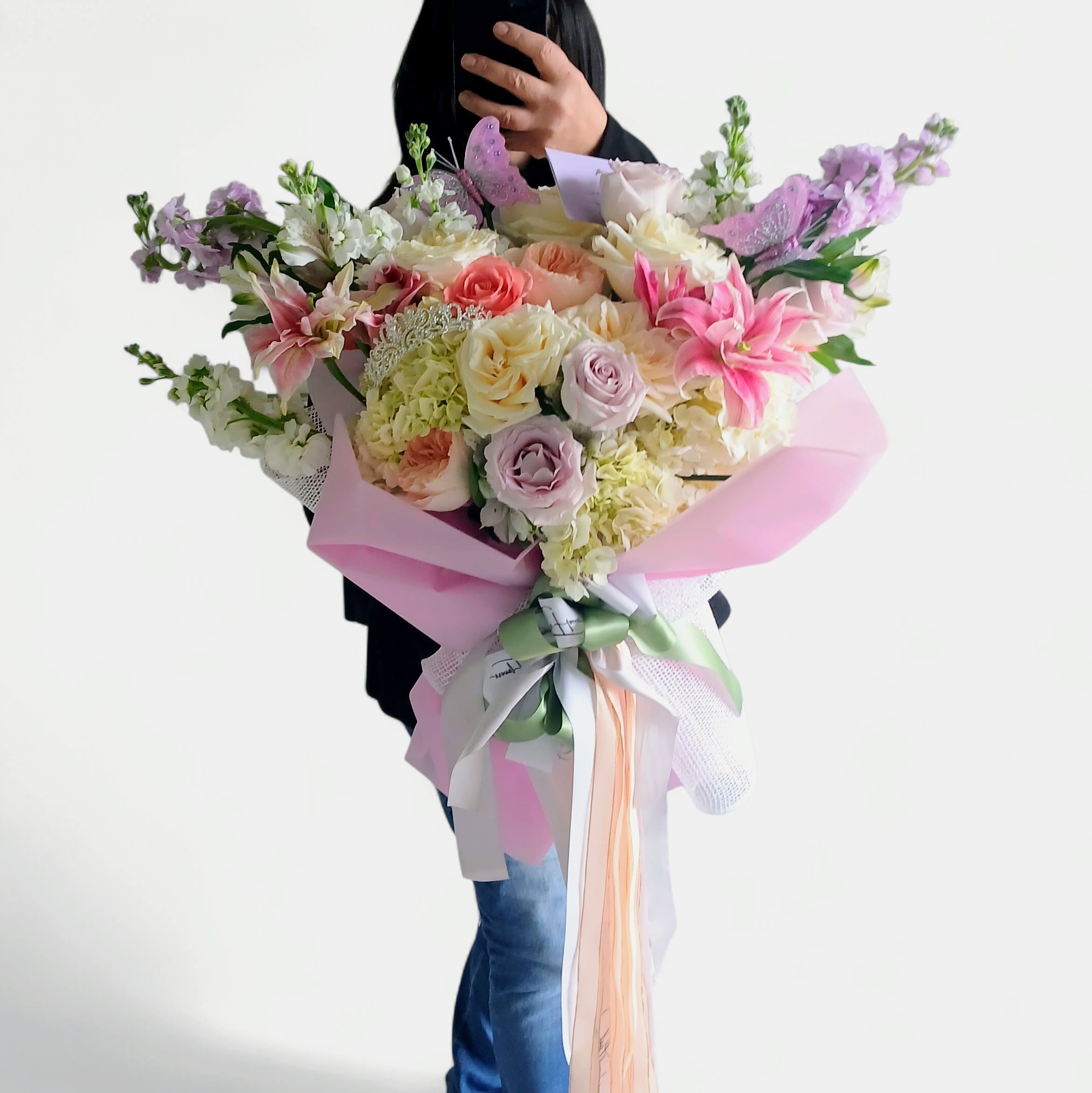 The Beautiful One Pink Bouquet - Send this beautiful all pink and lavender blossoms bouquet filled with roses hydrangeas and orchids adorned with a beautiful rhinestone tiara that she can wear and save as a keepsake. Perfect to send for every reason to make their day, wrapped in pretty pink paper and mesh with a long flowing rose pink satin bow with butterflies.