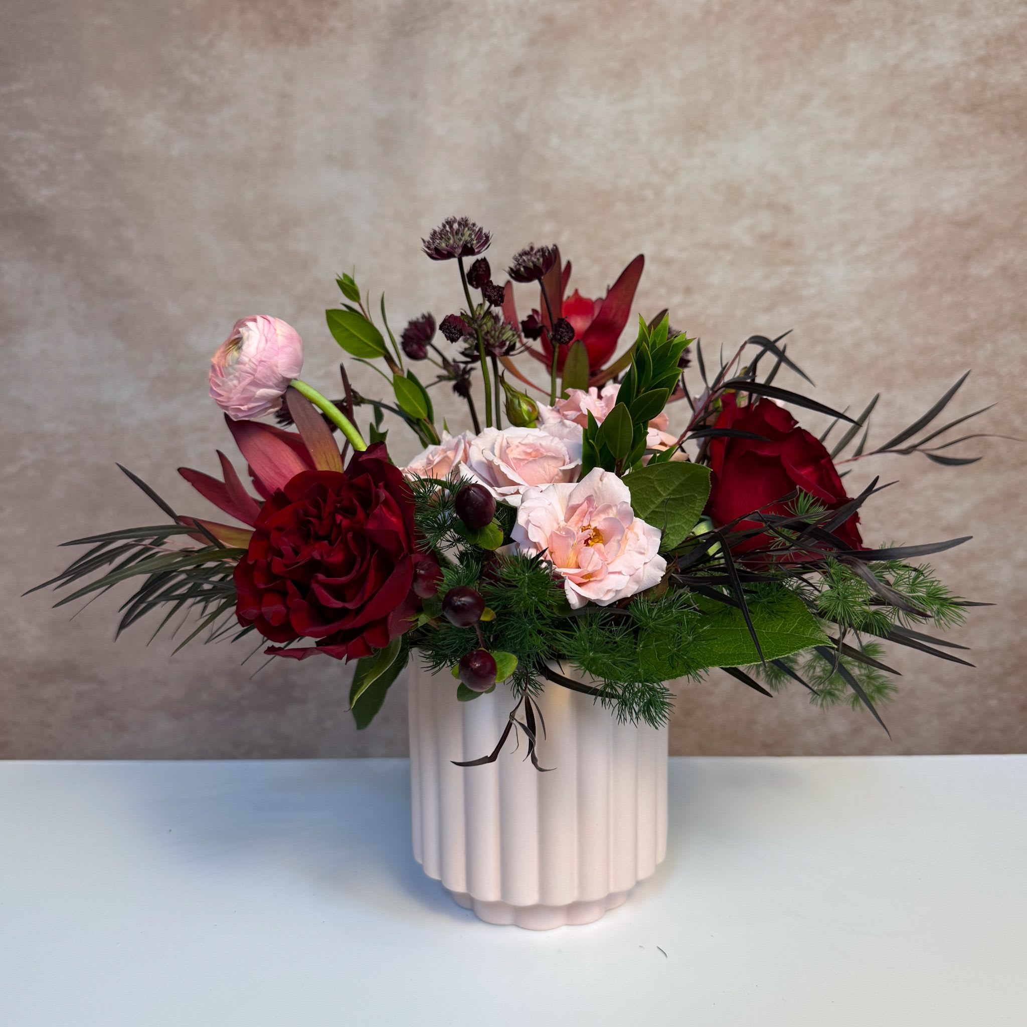Love Potion - Be bold and send this showstopper arrangement filled with bright jewel tones in a large black vessel. Upgrade to deluxe and premium for additional luxe blooms. 