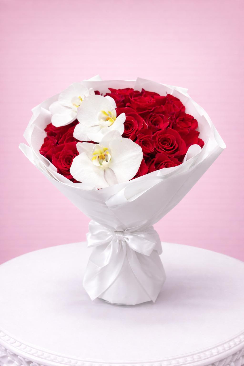 MEMORABLE - 25 Red Roses A beautiful bouquet of 25 red roses accented with elegant white orchids, wrapped in crisp white paper for a romantic and refined look. 