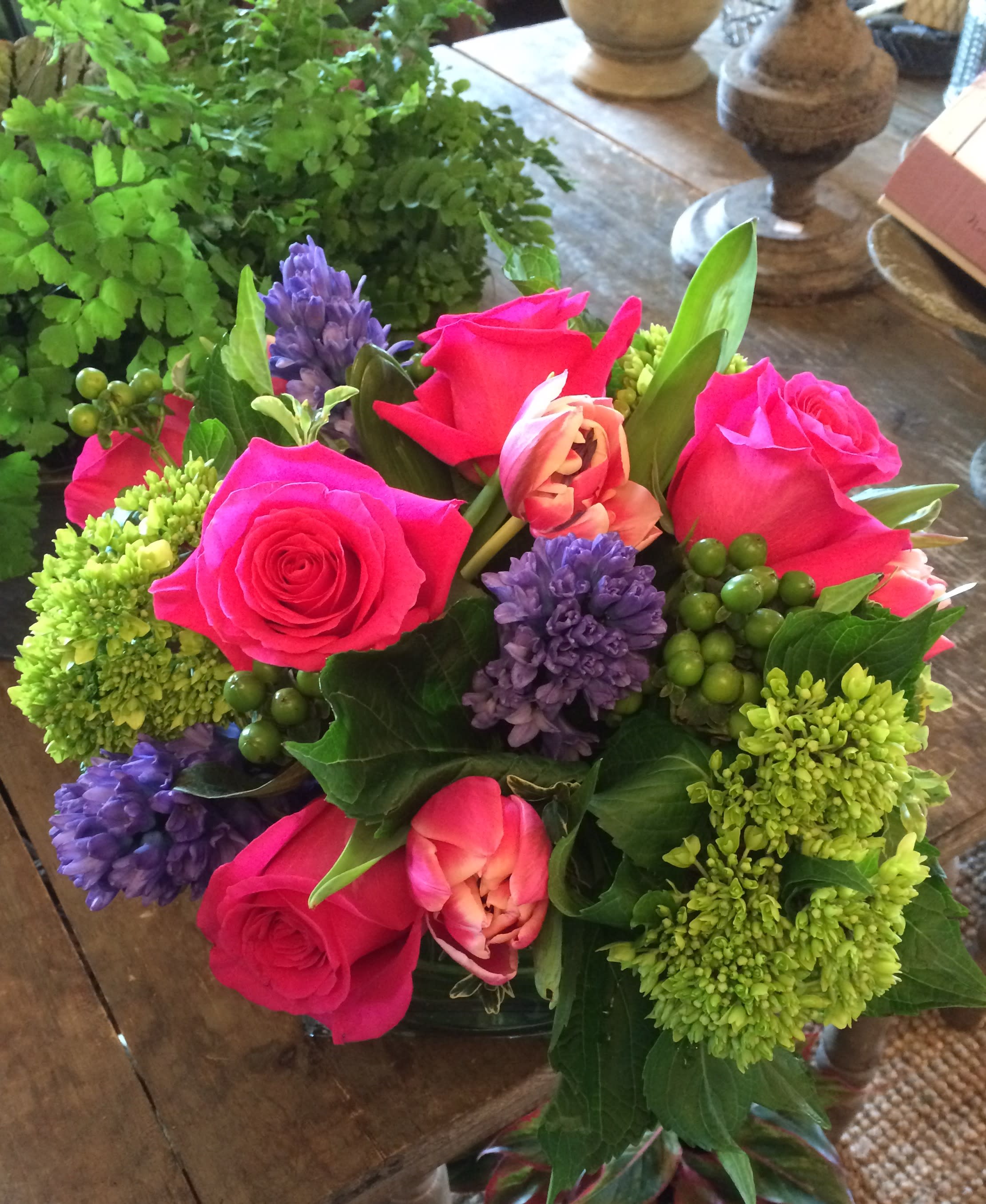 Blushing Spring Cube - Mix of Full Monty roses, tulips, green hydrangeas and hypericum accented with stunning blue hyacinths (when available) or Iris in a leaf lined 6" cube.