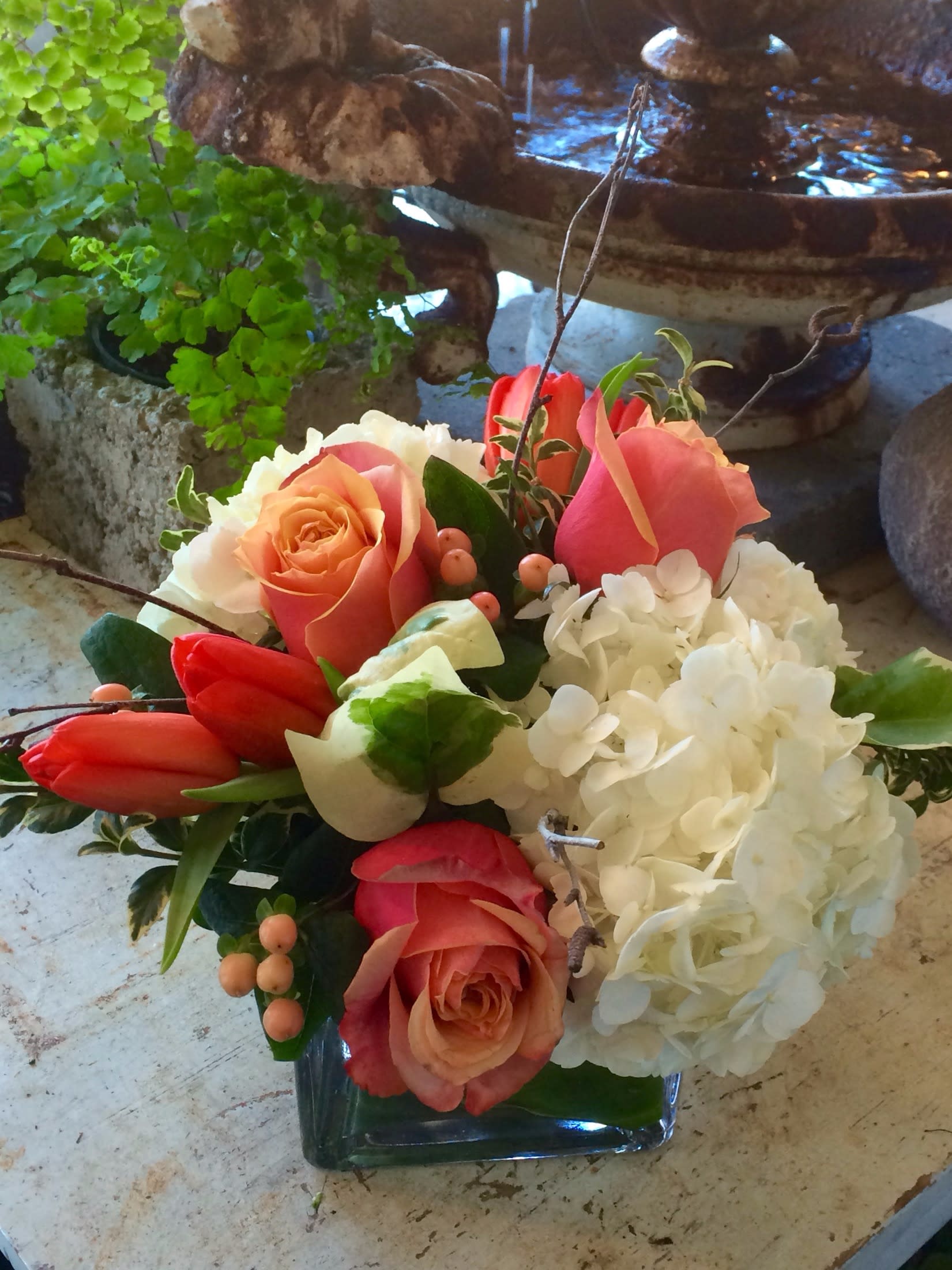 Cherry Brandy Spring  - Vibrant mix of orange tulips, white hydrangeas and Cherry Brandy roses accented with peach hypericum and mixed variegated foliage.