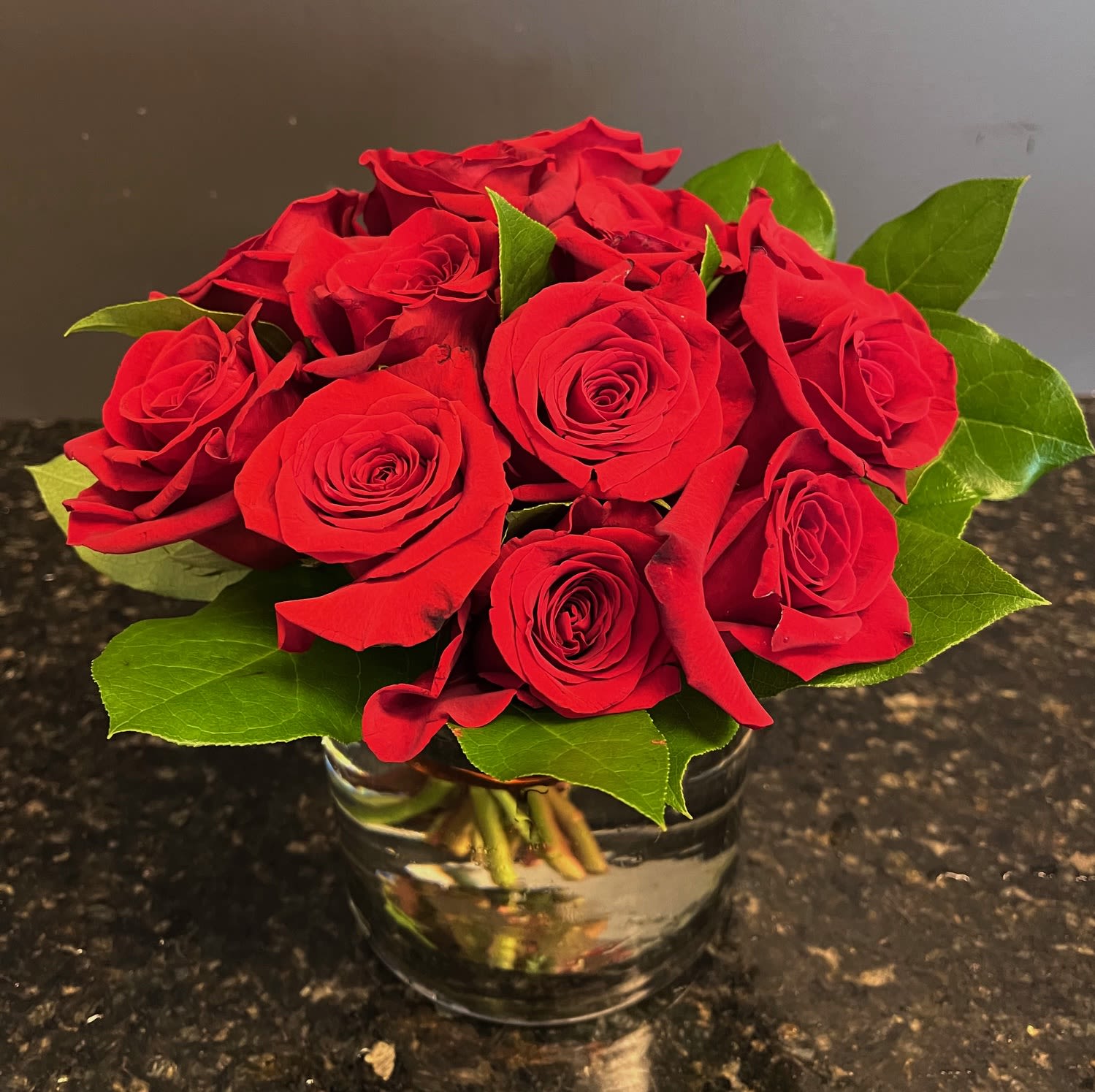Short and Sweet - enjoy this modern twist on a dozen roses, cut short with fresh greens and wrapped with wire