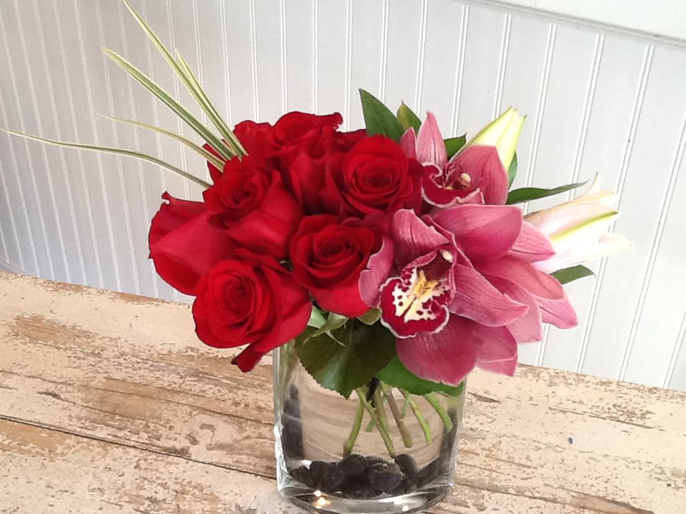 Love's Purity - Red Roses and cymbidium orchids gently nestled into greenery.  