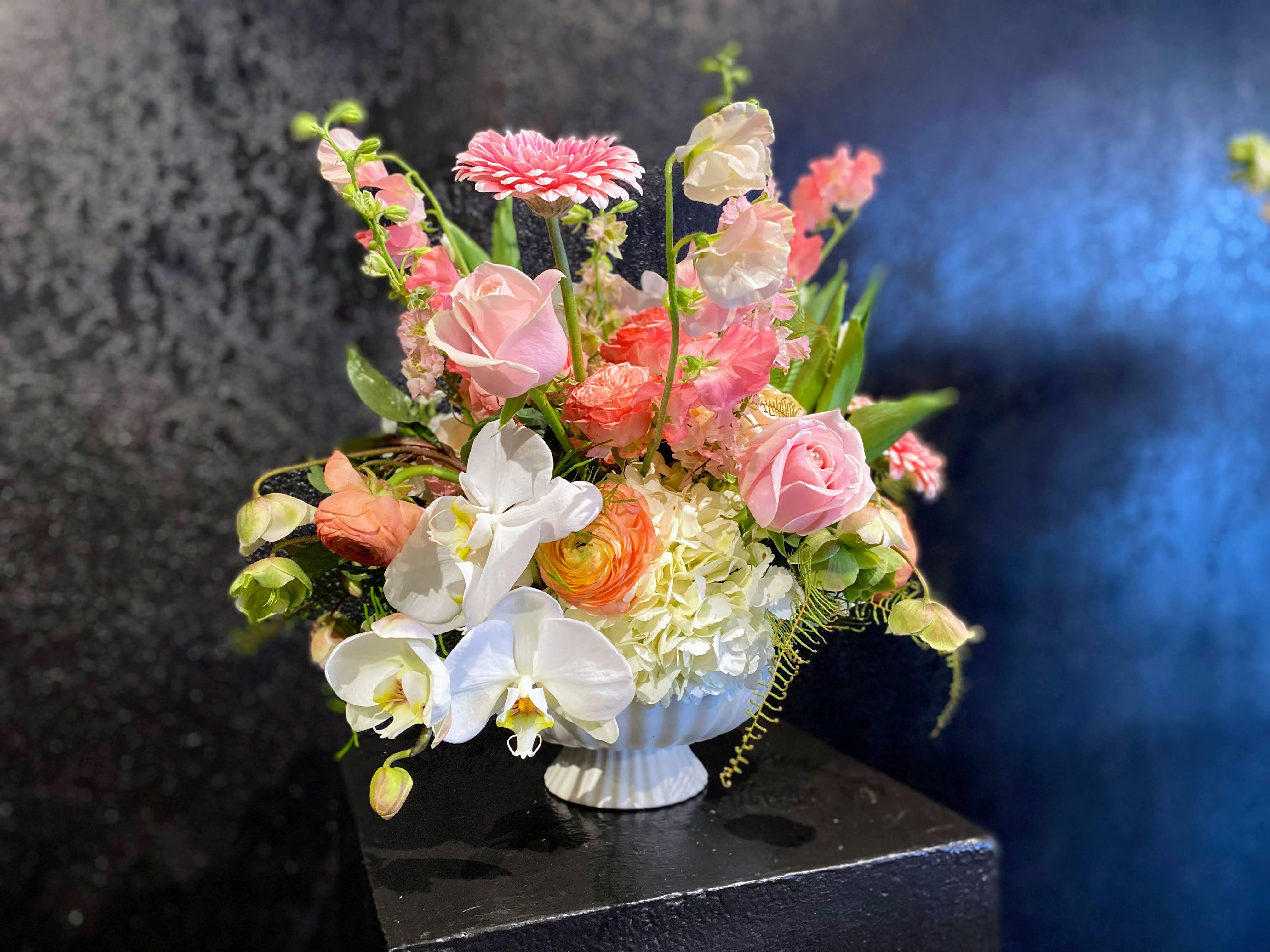 #24 - Eternally Yours - Our lush and luxurious design is an ode to the garden-style arrangement.  A chicken-wire armature inside this unique footed ceramic bowl allows us to fill this arrangement with delicate and fragrant Spring materials, proving sustainable techniques have a lot to offer. Container type may vary depending on availability, measuring approximately 6x6". Some substitutions may apply.