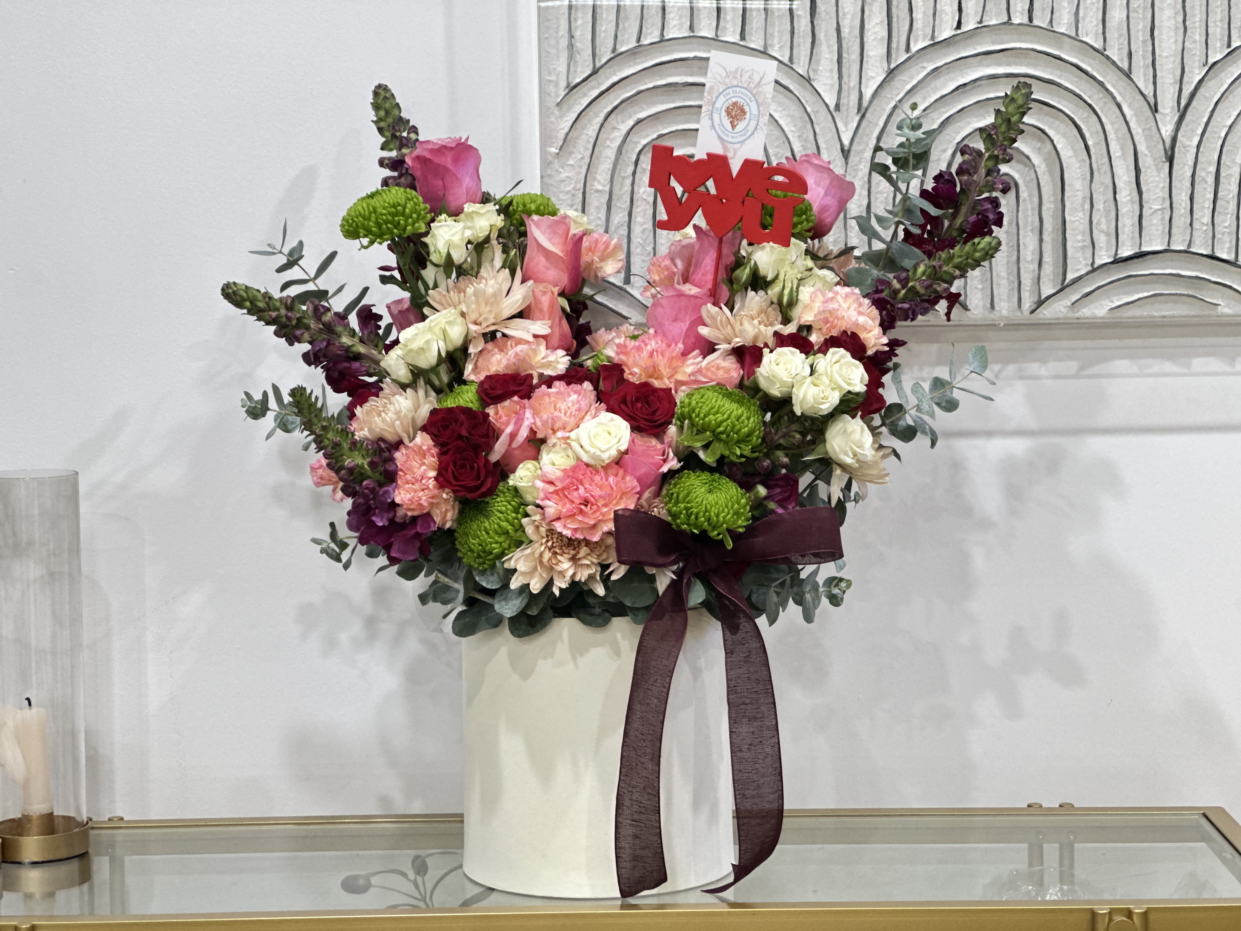Floral Divine  - Floral Divine is a sophisticated floral creation that celebrates beauty, abundance, and divine detail. Designed in an elegant white vase, this arrangement features a harmonious blend of blush, wine, and cream roses, delicate carnations, vibrant green chrysanthemums, and fresh foliage that adds movement and freshness.  Each bloom is carefully selected and thoughtfully placed to create a rich composition full of texture, volume, and elegance. Floral Divine conveys feelings of love, gratitude, and refinement, making it a stunning statement piece for any meaningful occasion.  Perfect for: anniversaries, special birthdays, heartfelt thank-you gifts, elegant celebrations, or simply to surprise someone with something truly unique and memorable.  Floral Divine is more than a floral arrangement—it’s a divine expression from the heart.