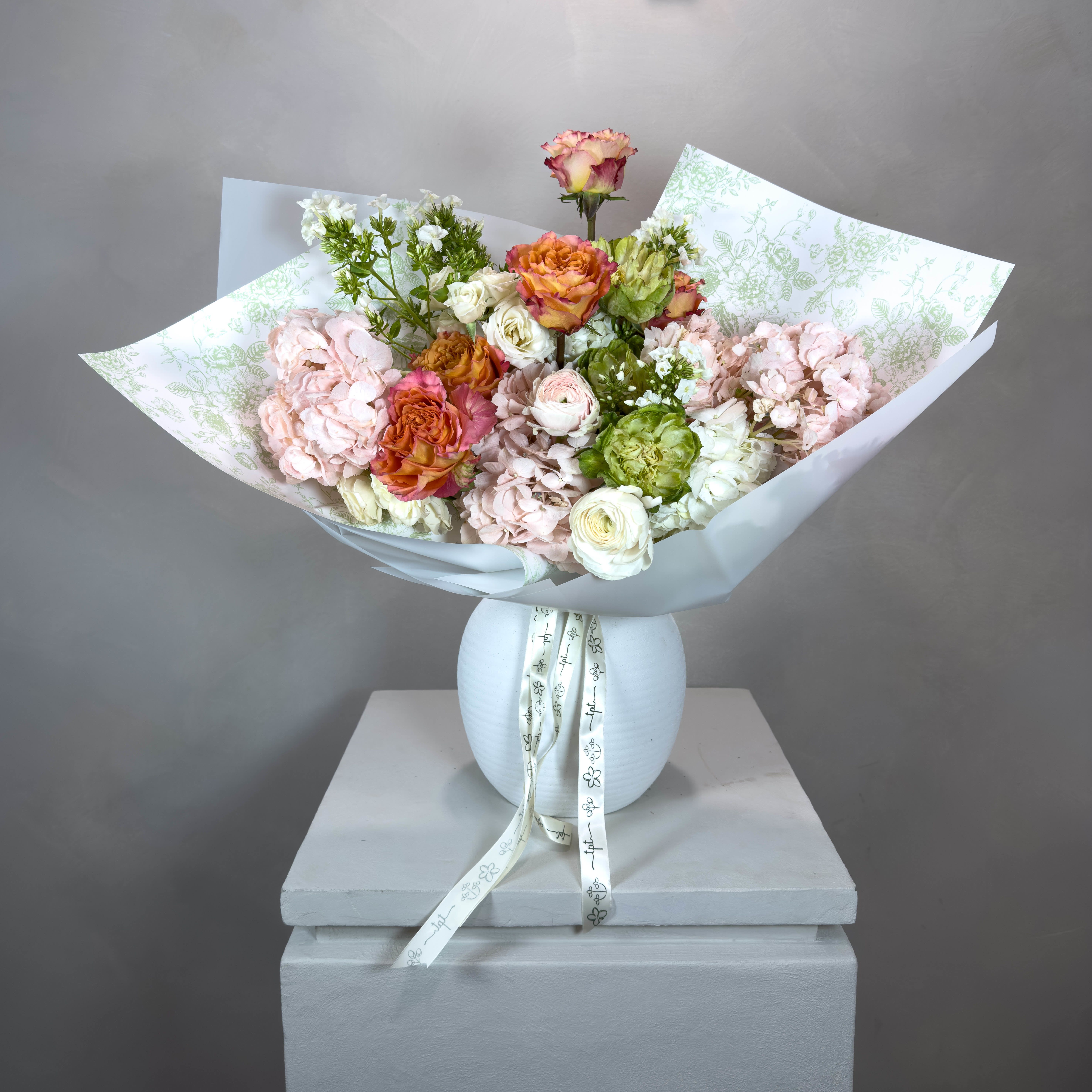 Songeun Petal Designer’s Choice Bouquet - Our Petal Designer’s Choice Bouquet features a hand-selected assortment of the freshest seasonal blooms, thoughtfully arranged and elegantly wrapped in Korean-style wrapping for a modern, artistic presentation. Each bouquet is completely unique - colors, textures, and flowers vary with the season and availability, ensuring that no two bouquets are ever the same.   Every bouquet includes a handwritten note, which comes with care instructions for your blooms.  All bouquets come with a carry-out bag, and bouquets of 18 stems or more include a water pouch in addition to the bag for easy transport.  PLEASE NOTE:  Delivery orders should be placed 2–3 days in advance. For same-day delivery, please call or text us at 704.975.2774 to check availability.  FINAL SALE POLICY:  All orders are final sale. Due to the custom and perishable nature of our floral designs, we are unable to accommodate cancellations, refunds, or exchanges once an order has been placed. Each arrangement is made uniquely for you, with care and attention to detail.  Images are for inspiration only - we do not replicate past designs or recreate another florist’s work. Each bouquet is handcrafted with creativity, intention, and care.