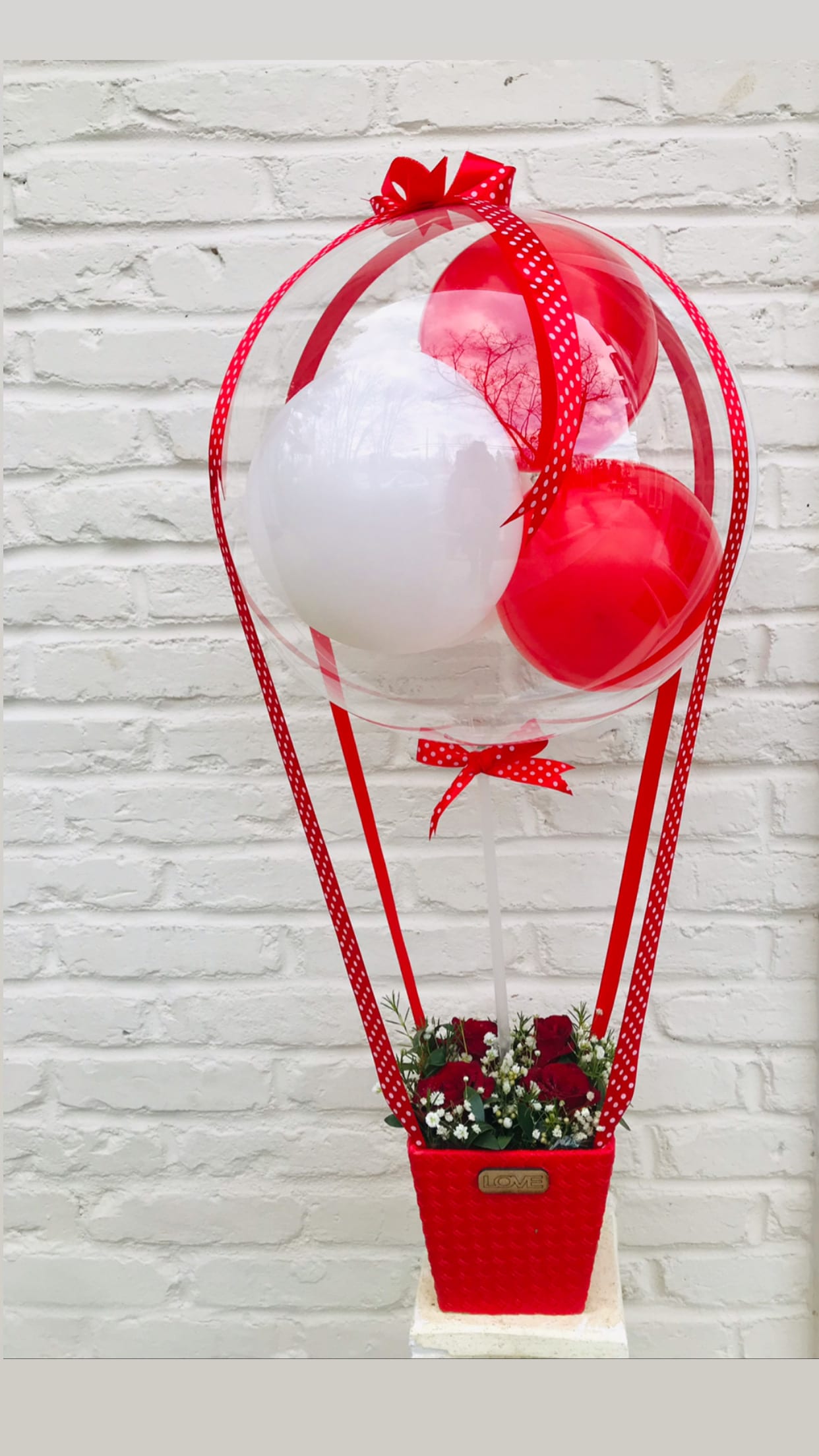 Loving Balloon and Roses Arrangement  - Red roses arranged in a box, elegantly accented with a stuffed balloon perfect for the occasion. Standard size has four roses, Deluxe size has six roses, Premium size has nine roses.   NOTE: The colors of the balloons can also be customized, we can create the arrangement in any color combination you’d like.