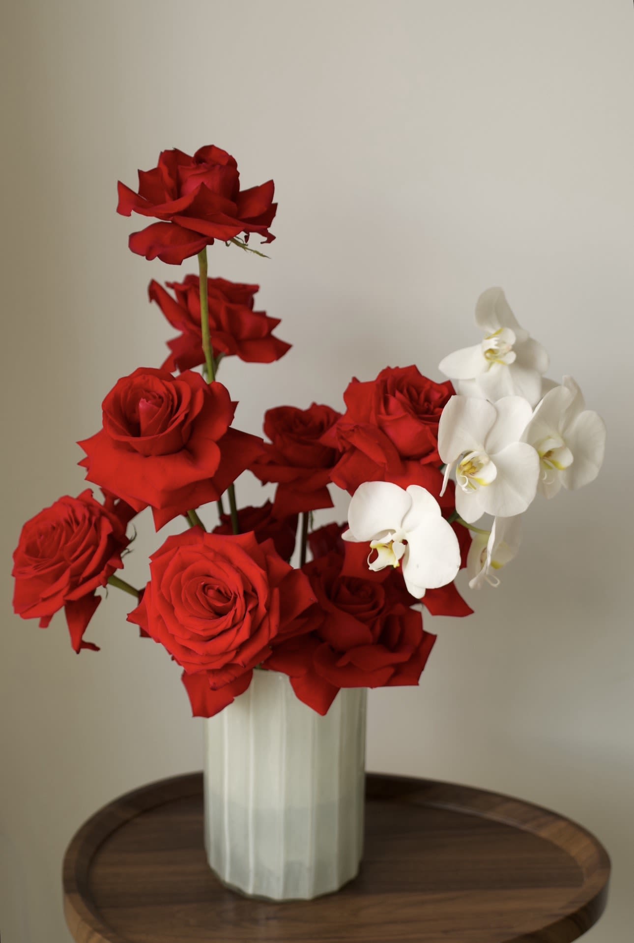 Red Vogue - A bold and elegant arrangement featuring sculptural red roses accented with pristine white orchid blooms.   Designed in a modern ceramic vase, this piece blends passion with refined minimalism, creating a powerful visual statement.   Perfect for luxury gifting, romantic occasions, or elevated interior styling.