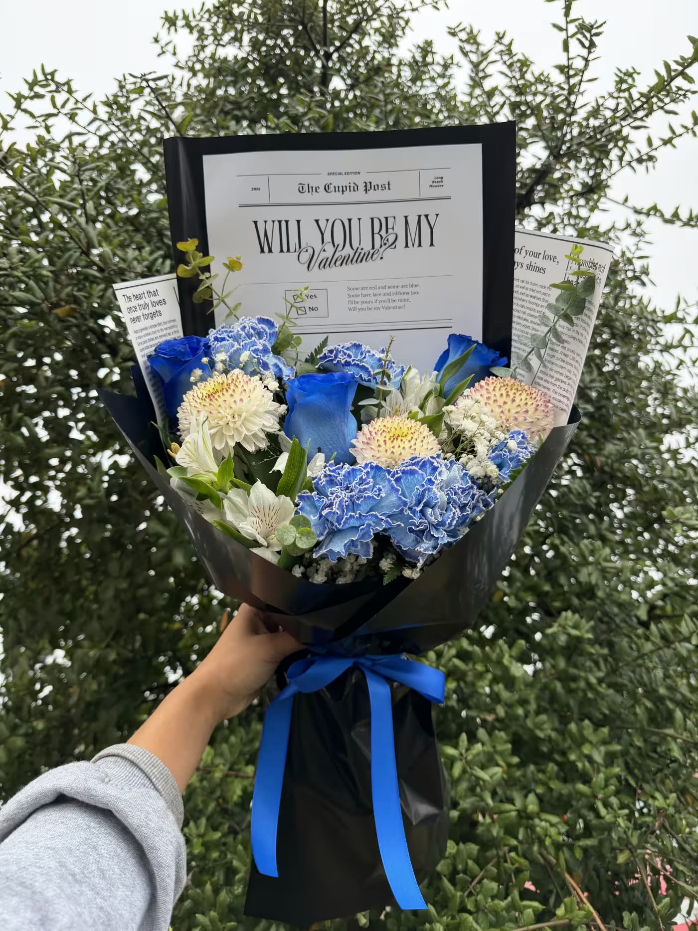 “Be Mine?” Blue - Will you be my Valentine’s Day” handheld bouquet. Designer’s choice mixed flowers.  Color scheme is not limited the one shown in the photo. PLEASE PROVIDE YOUR PREFERRED COLOR SCHEME AND ADD TO “NOTES”