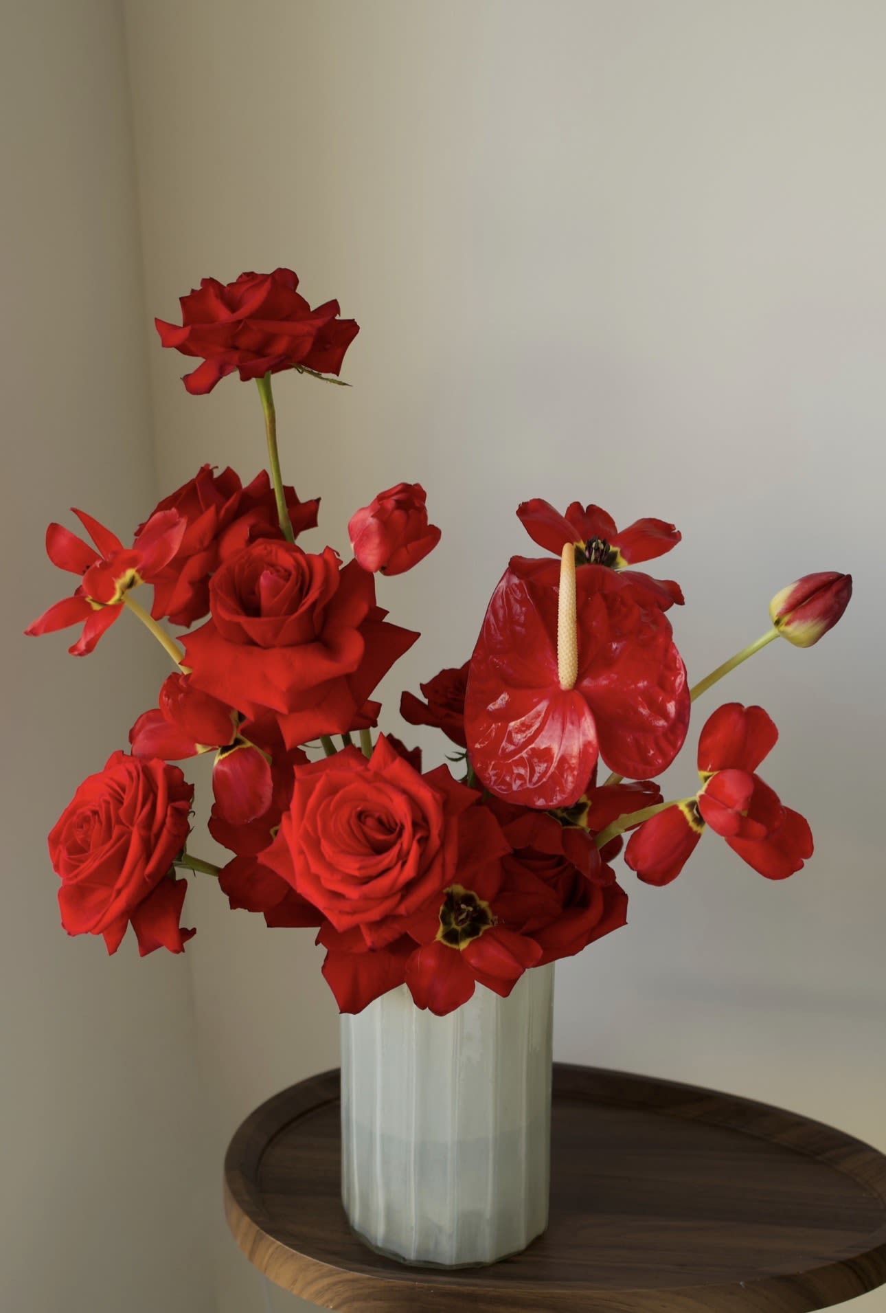 Scarlet Elegance - A bold red floral statement featuring premium roses, sculptural anthurium, and seasonal accents, arranged in a minimalist ceramic vase.   Striking, modern, and expressive — designed to make an unforgettable impression.   Perfect for a powerful gesture, romantic moment, or refined interior styling.