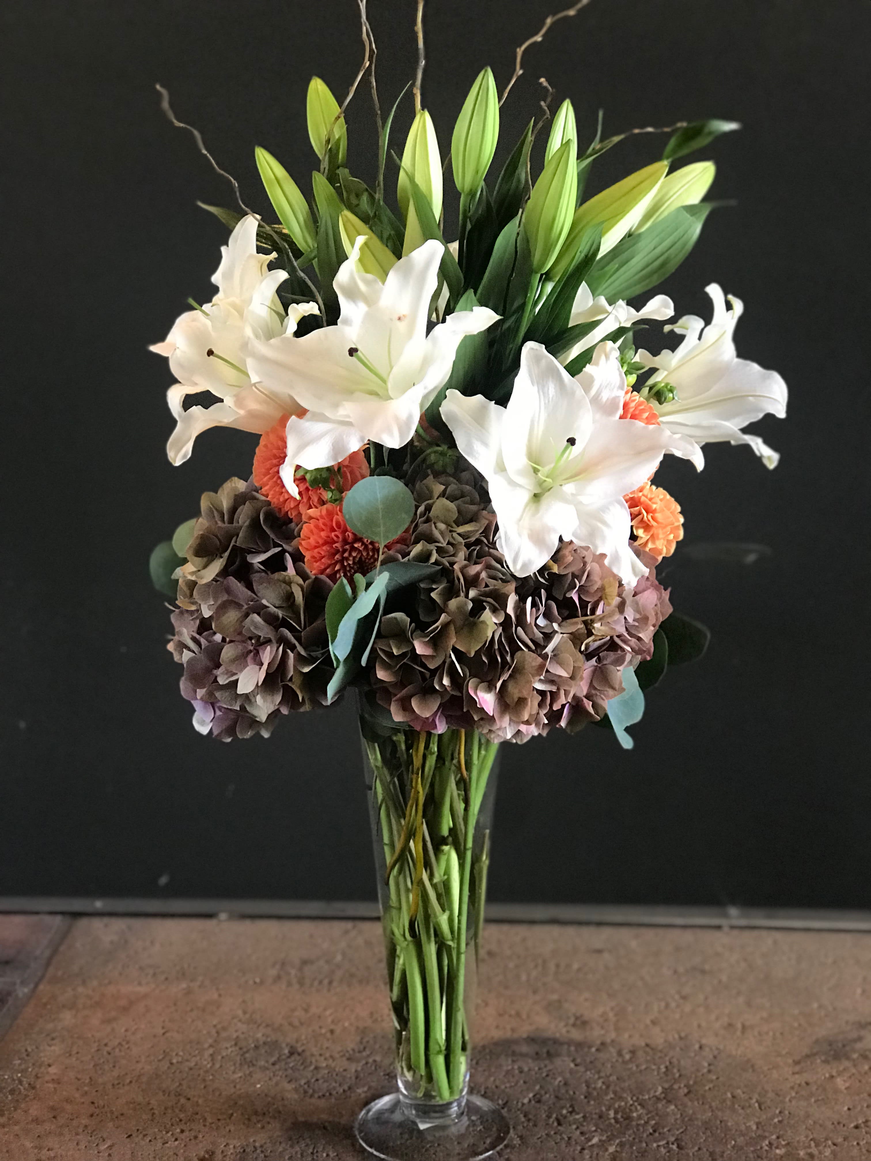 Antique Hydrangea Bouquet - Casa blanca lilies mixed in with antique hydrangeas, dahlias, silver dollar eucalyptus and curly willows in a clear glass vase. 