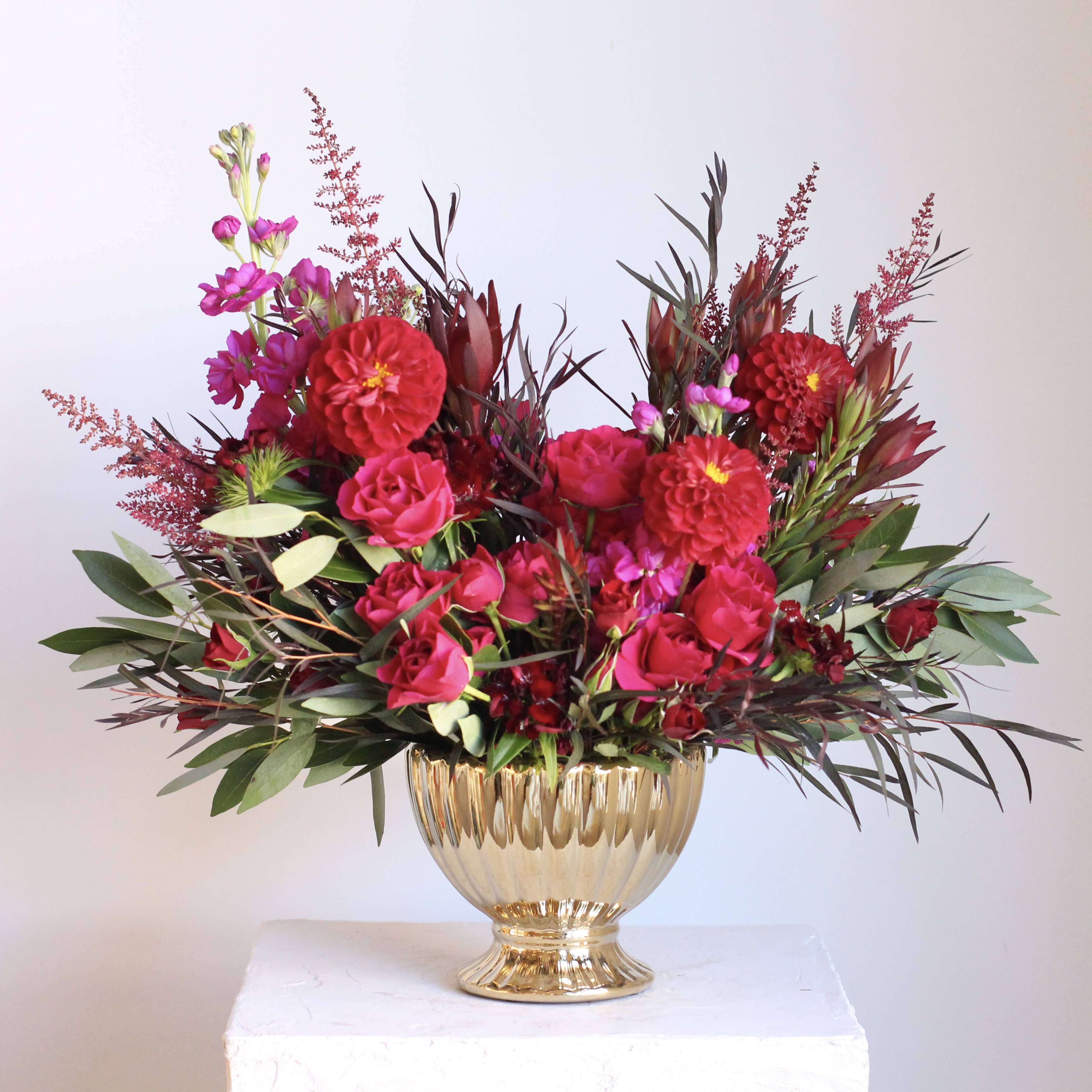 Deluxe Rouge - Bold, romantic, and full of drama, the Rouge floral arrangement is a stunning blend of deep reds, burgundy, and magenta blooms. All showcased in an elegant gold container, it’s perfect for any occasion that calls for a touch of luxury!  Delivery Policy: At Middlemist, we aim to make every delivery seamless and delightful. It is the sender’s responsibility to ensure the recipient is available to accept delivery between 3–5pm on the scheduled date and that the delivery address is accurate. We will send a text notification to the recipient on the day of delivery. If no one is available to receive the order, it will be returned to the shop and may be picked up or redelivered for an additional delivery fee. If a recipient requests the order be left unattended, we cannot guarantee the condition of the flowers or plants, and no refunds will be issued once an order is left outside.