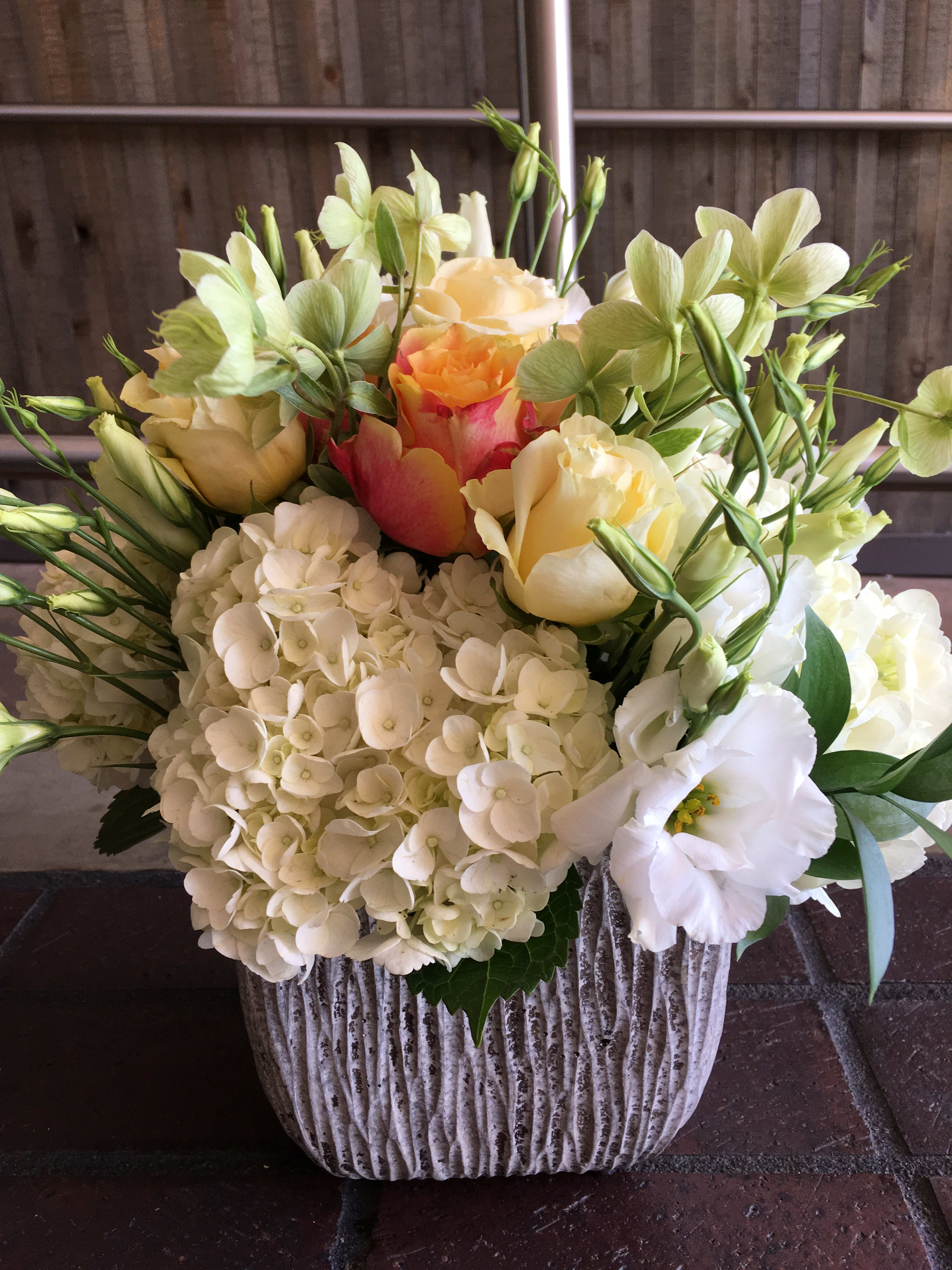 Helleborus Design - A mix of hydrangeas, lisianthus, roses, and helleborus designed in beautiful rustic ceramic vase. 