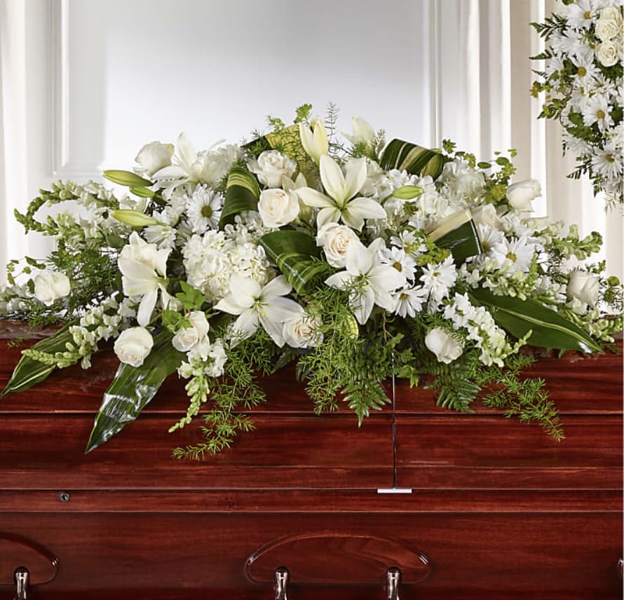 Timeless Casket Spray - This Casket Spray Composed of roses, snapdragons, lilies and hydrangea, this luminous collection of white and ivory hues comes together to create an elegant tribute.  This Spray is approximately 13"H x 49"W.  Rose Snapdragon Lily Hydrangea