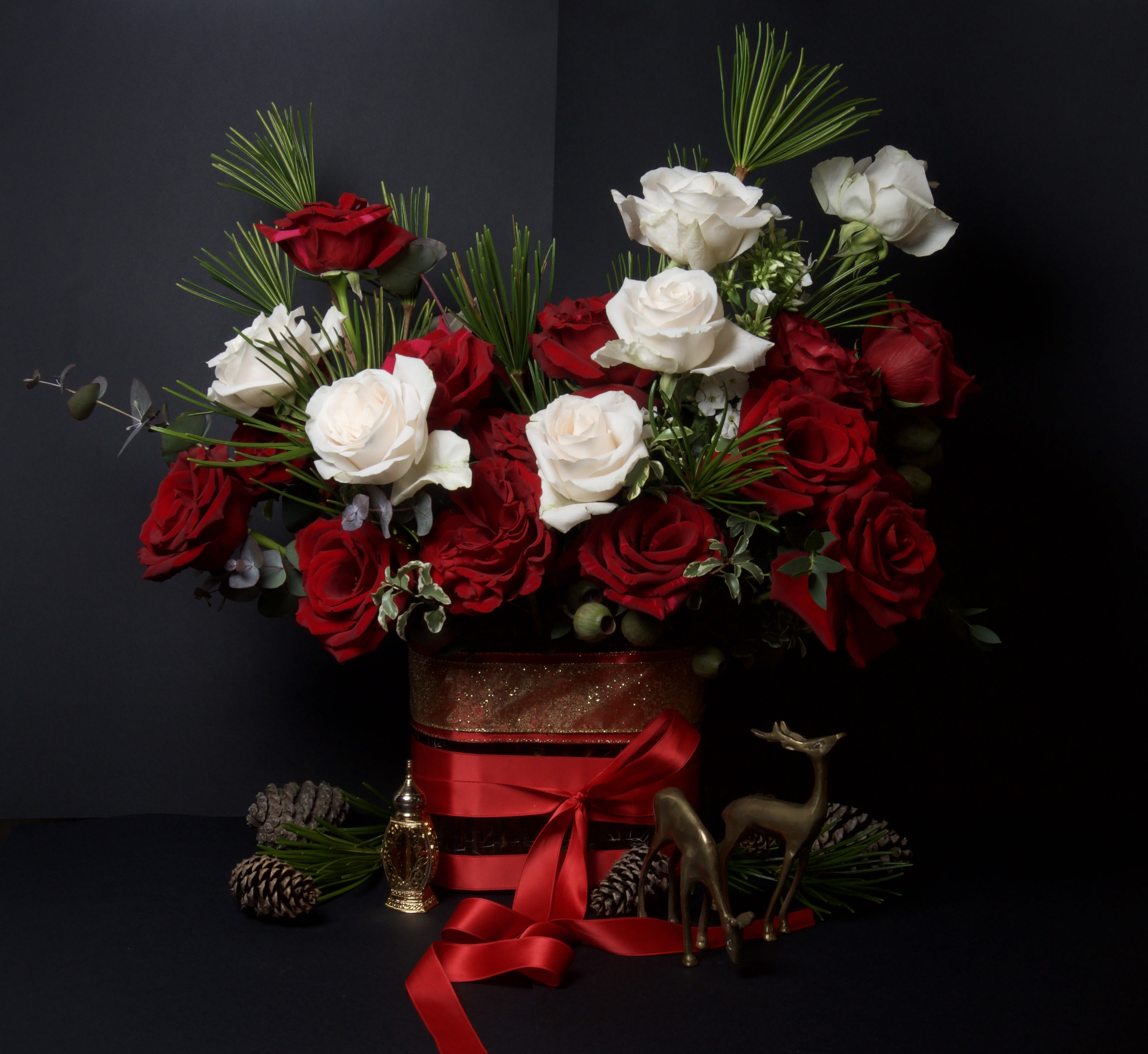 Madison - 34 - This elegant arrangement features a striking blend of rich red and creamy white roses, accented with seasonal greens for a classic holiday look. The contrast of colors creates a timeless design that feels both festive and romantic, making it a beautiful choice for winter celebrations or Valentine’s Day.  Roses have long symbolized love and devotion, and this arrangement offers a graceful way to express those sentiments. Whether displayed during the holidays or given as a meaningful gift in the heart of winter, this arrangement brings warmth, beauty, and lasting impression to any space.