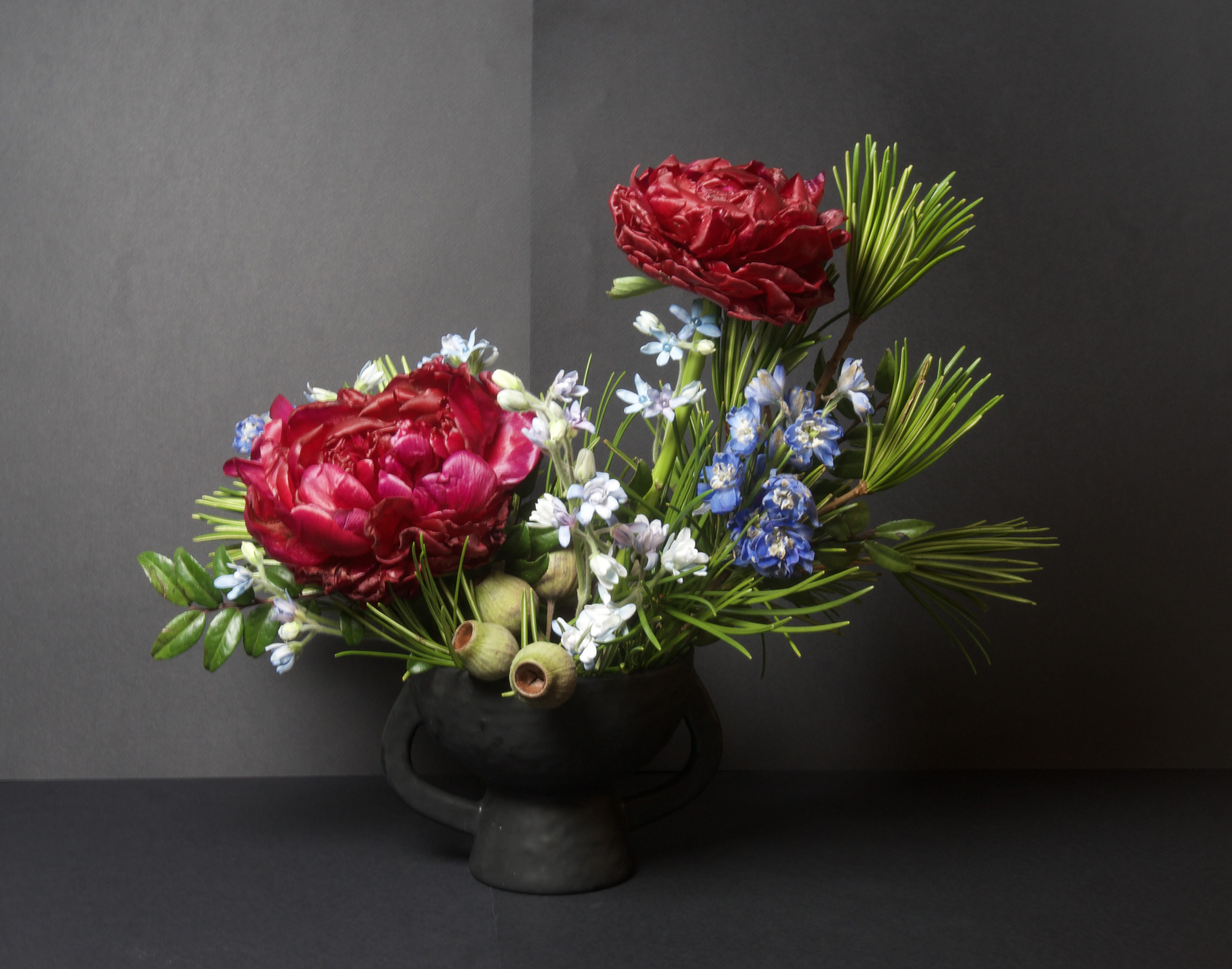 Canal - 41 - This modern ikebana arrangement highlights bold, textural blooms arranged with intention and balance. Rich florals are paired with seasonal accents and sculptural greenery, allowing each element space to stand on its own while contributing to a striking overall form.  Designed with simplicity and movement in mind, this piece draws the eye through contrast and line, offering a quiet yet powerful presence. A beautiful choice for those who appreciate artistry, restraint, and thoughtful design.