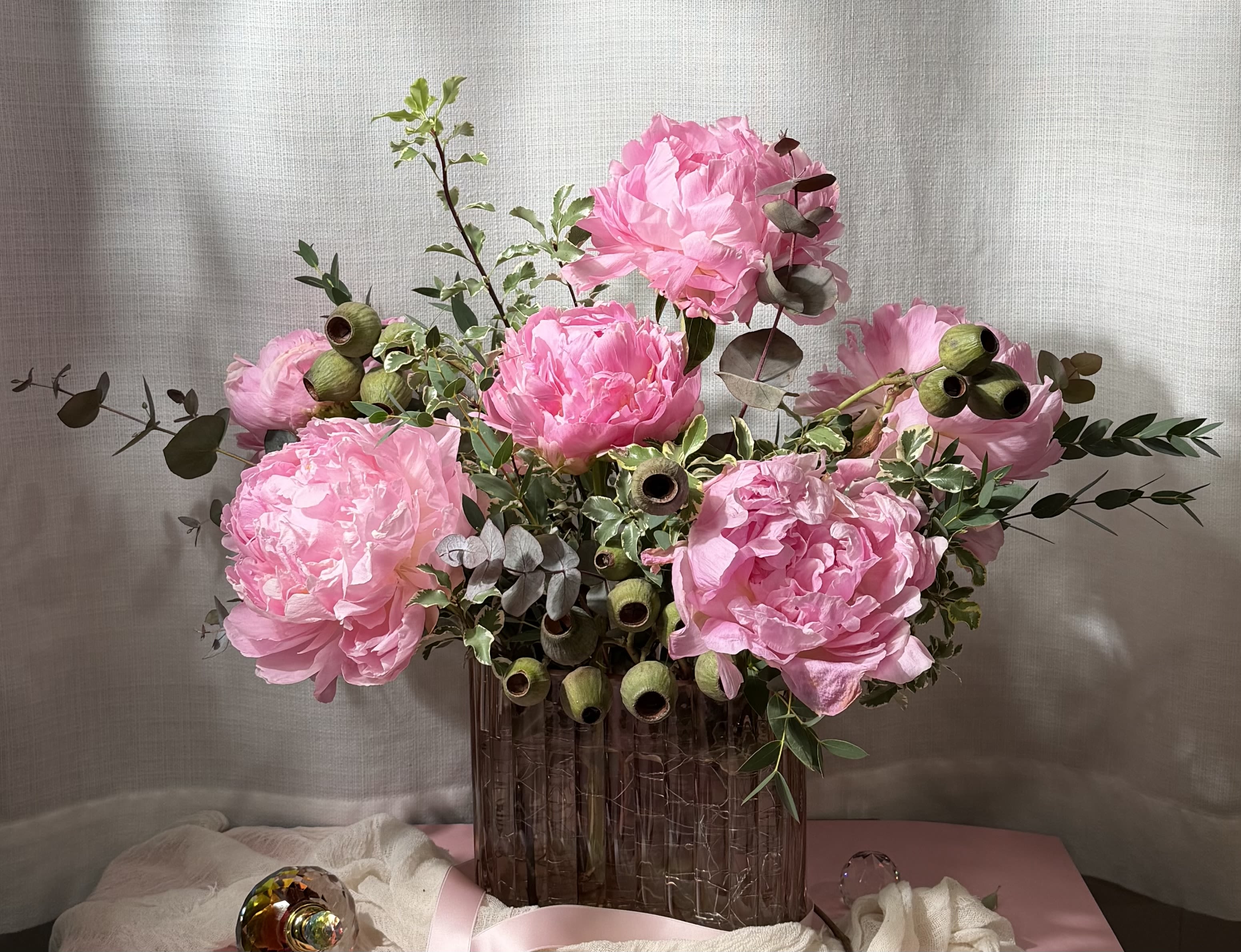 Riverside - 156 - A beautiful arrangement of large bloom peonies accented with variegated pittosporum, pistachio eucalyptus, eucalyptus pods, and stuartina eucalyptus. Each bloom showcases layers of soft delicate petals. This bouquet is sure to capture the attention of that special someone. 