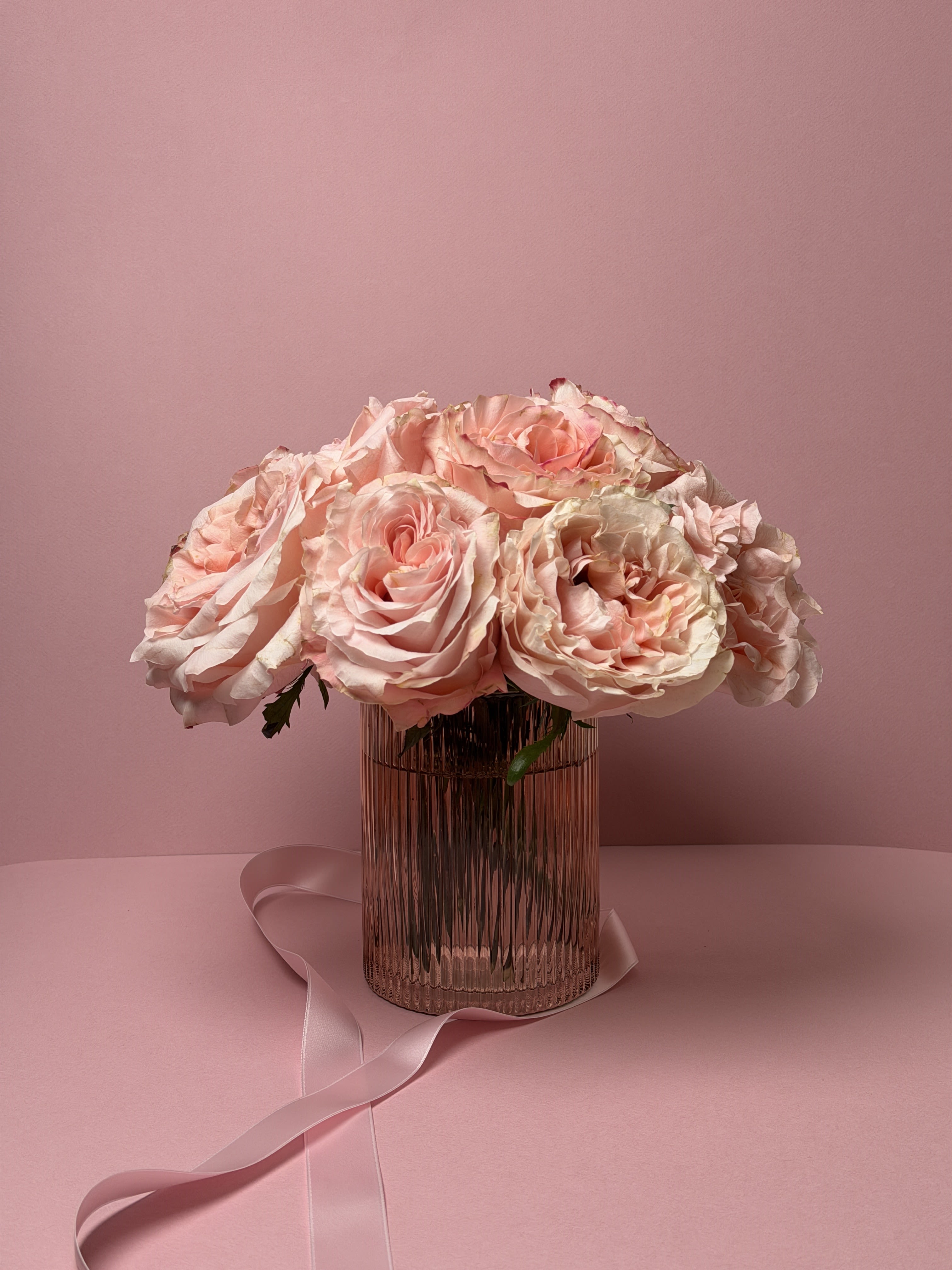 Mercer - 81 - A beautiful display of color using lush, romantic roses. These elegant blossoms are chosen for their soft blush tones and full, expressive petals, creating a look that feels both graceful and timeless. Perfect for that special person, this arrangement offers a refined way to express love, admiration, and thoughtfulness.  Designed in a classic pavé style, the roses are arranged closely together to create a rich, luxurious presence while maintaining a calm and balanced appearance. Whether given for Valentine’s Day or simply to mark a meaningful moment, this arrangement makes a lasting impression without feeling overstated.  This arrangement is available with 12 roses (pictured), 24 roses, or 48 roses, thoughtfully arranged in a low glass vessel.