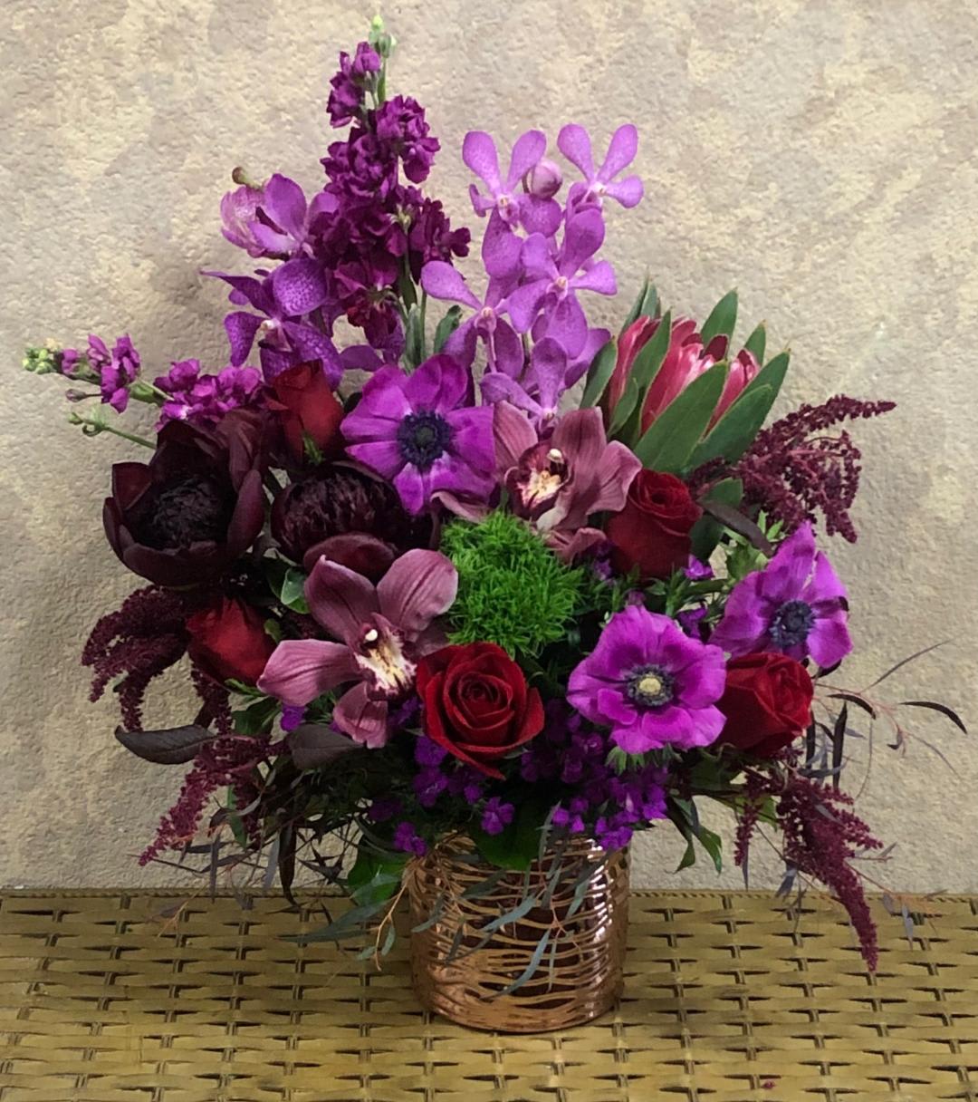 Take My Love Higher - Recipe:  Give your sweetheart this red, Fushion, Tropical piece with Burgundy Peonies (seasonal), Cymbidium Orchids, Orchids, Pink Stock, Fushion Anemones (seasonal), Protea, Red Roses, Sweet William, Dianthus barbatus, Amaranthus, Button Mums in a rose-pink circular vase.  Availability: Seasonal Anemones: Winter (Nov-March), end of Summer- (August) Peonies: November- mid-August Design View: Symmetric Front Facing View Photo shown: Standard and Deluxe available 