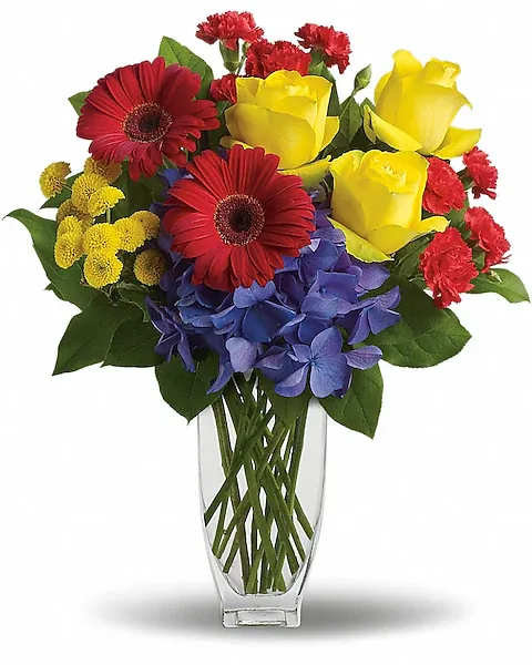 Here's to You by Teleflora - Whether you are raising a vase to celebrate a birthday, a new job or any other occasion, here's the one to send. So bright, so beautiful, so colorful - men and women alike will appreciate your thoughtfulness.  Brilliant blue hydrangea, yellow roses, red gerberas and miniature carnations, yellow button spray chrysanthemums are delivered in an exclusive Jewel Vase. Here's to celebrating!  Orientation : One-Sided All prices in USD ($) Due to an increase in the cost of roses, some product prices may be impacted during the Valentine’s delivery period.