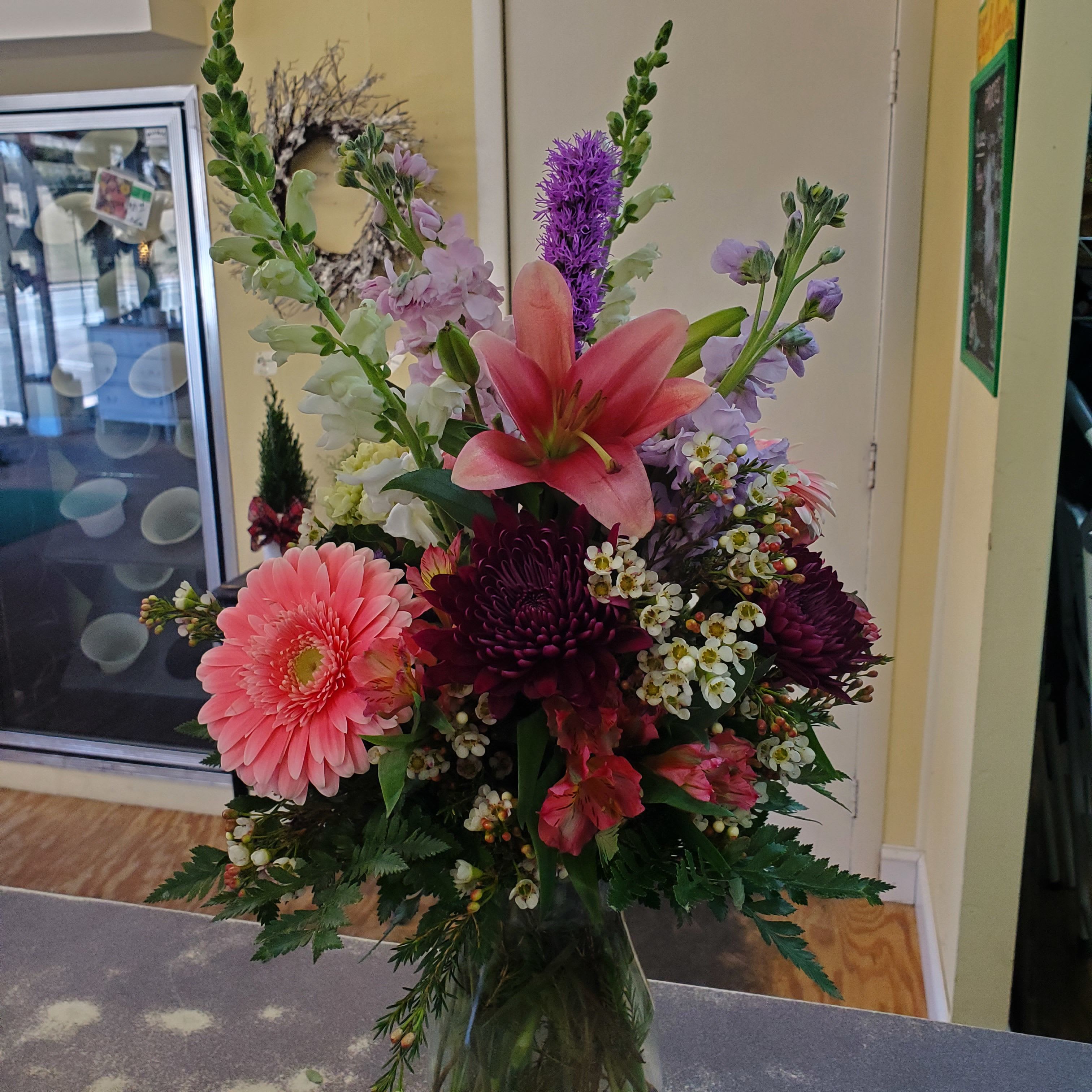 Pretty in Pink  - Tall glass arrangement designed in shades of light pink,  purple, mini green hydrangea and assorted natural greens. 