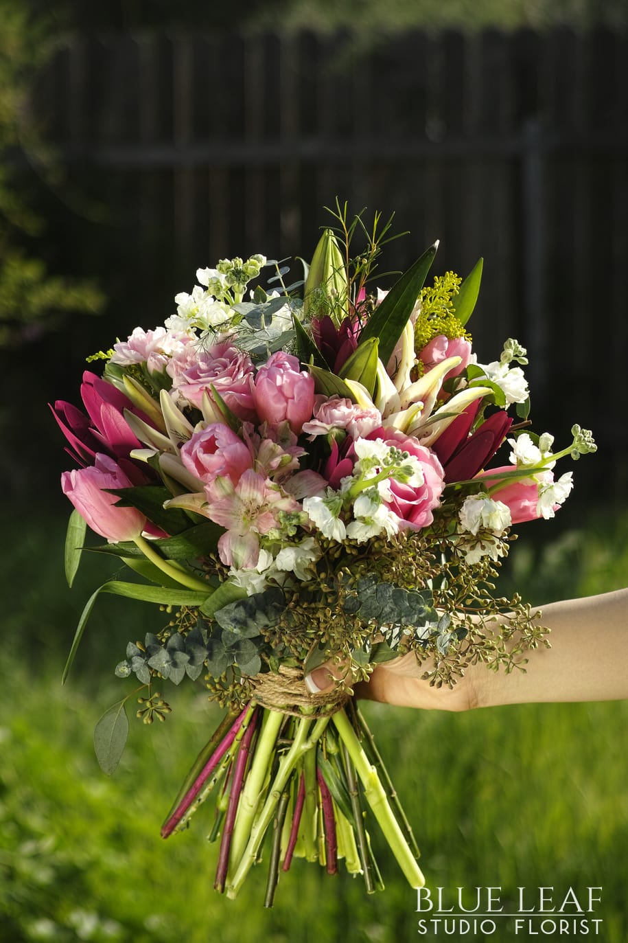 In The Sun - Custom hand-held bouquet with an assortment of pink and white; includes tulips, lilies, roses, stock, and other accent fillers. Hand-wrapped in brown butcher paper.