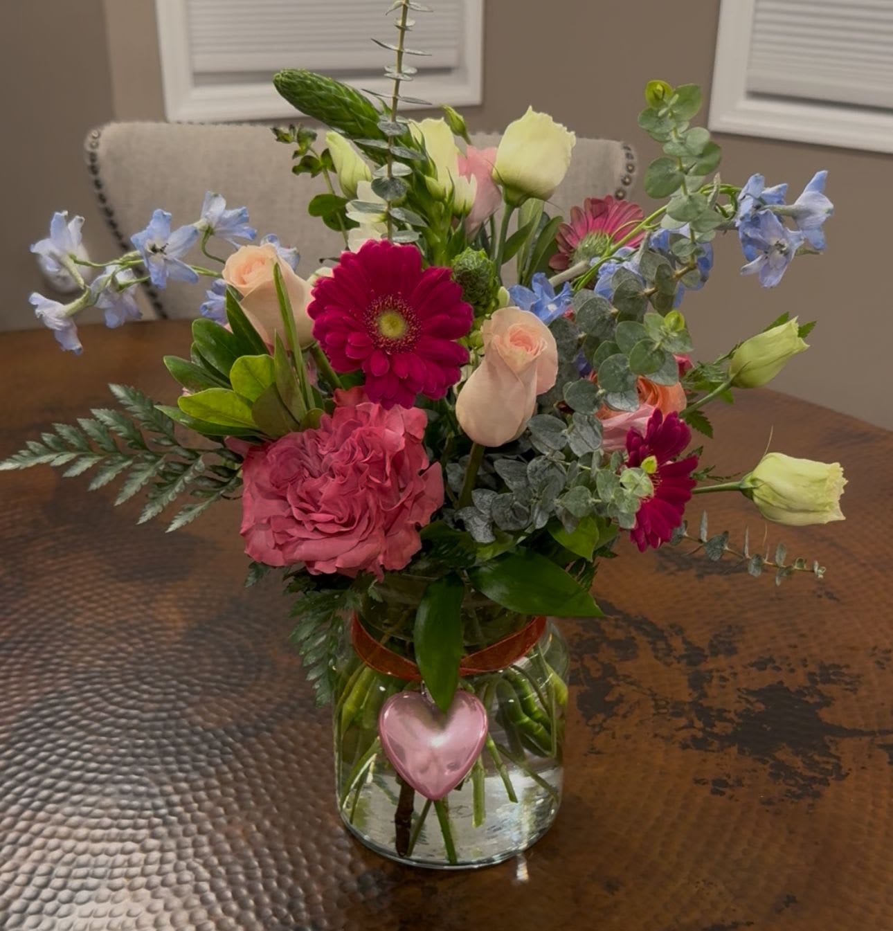 What a Gem - Hot pink jewel tones displayed in a garden style backdrop with day blue delphinium,  night star of bethlehem, eucalyptus, arranged with country blue roses in garden pink and fuchsia gerbera daisies.  