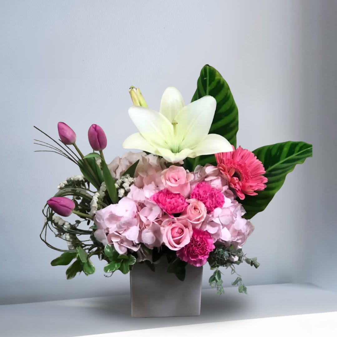 Santorini, Greece - Type of Flowers: White Lilies, Pink and White Hydrangeas, Pink Roses, Pink Gerberas, Pink Carnations, Purple Tulips and more in a square white vase. Availability: All year round Design View: Symmetric Front Facing View Photo shown: Regular