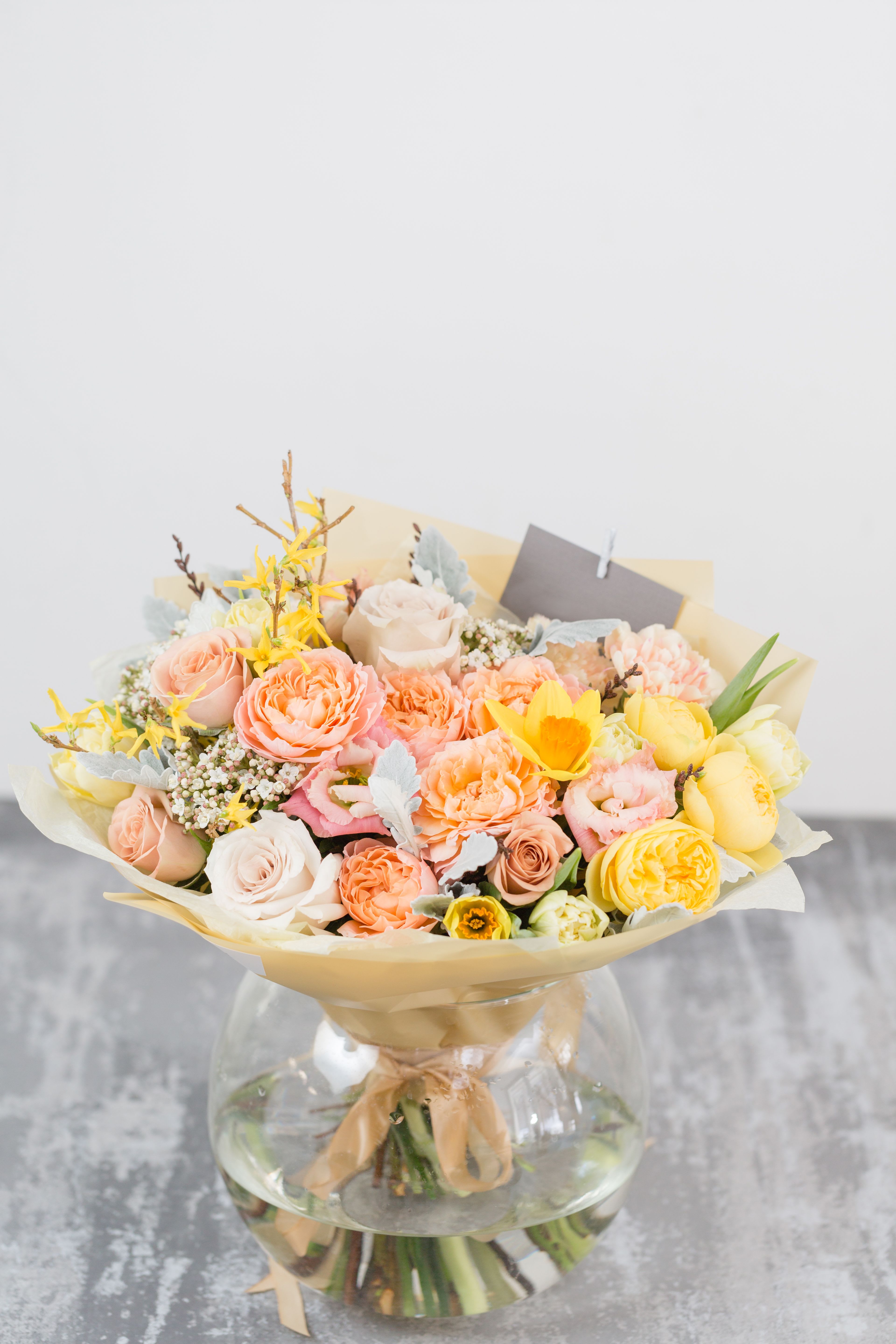 Golden Dawn Bouquet  - Fresh ,radiant, and full of joy, the Golden Dawn Bouquet combines soft peach roses, sunny yellow ranunculus, and pastel accents for a truly uplifting arrangement. Each stem is carefully selected to create a harmonious blend of warmth and elegance ,wrapped in soft tones and finished with a satin ribbon . Perfect for birthdays, anniversaries, thank you gestures, or simply brightening someones day.  Please note: Flower varieties may vary depending on seasonal availability. Substitutions of equal or greater value will be made to preserve the same style and beauty.