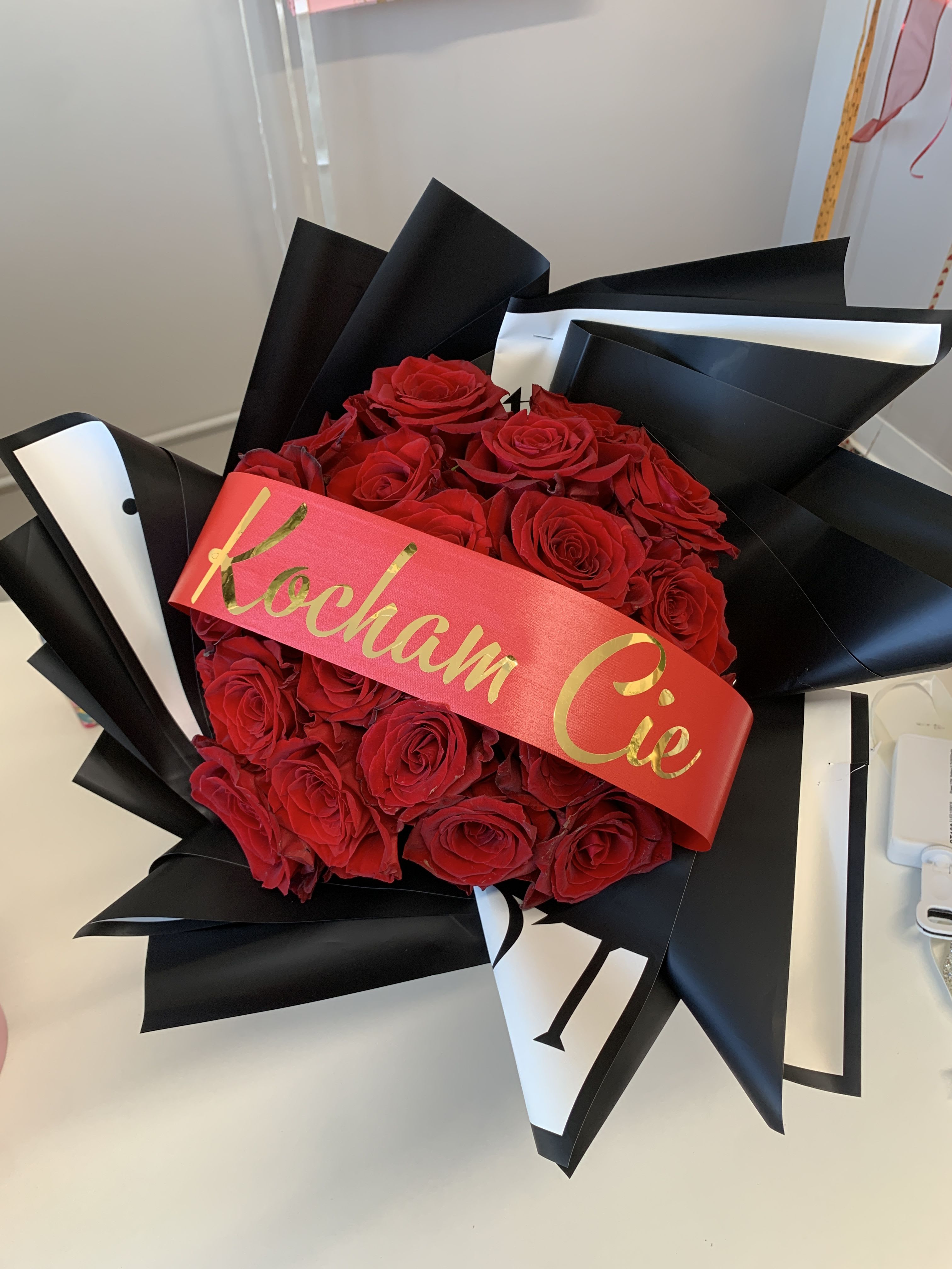 Love Is In the Air Ramo Buchon  - 25 Red Rose bouquet wrapped in black “Love is in the air” Korean paper.  Your choice of custom ribbon. 